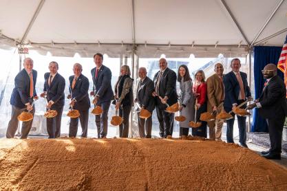 Several people dig shovels of dirt at the groundbreaking of the Manning Center