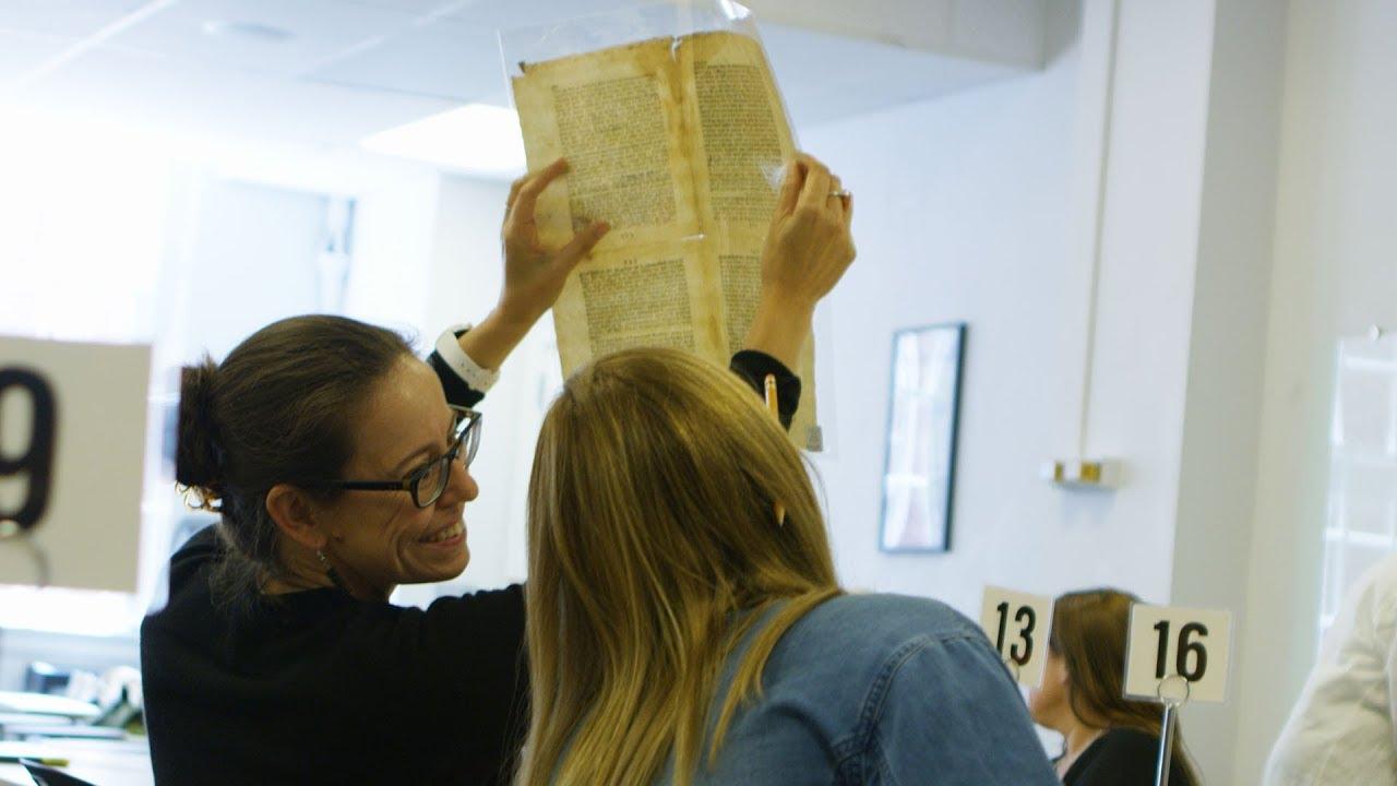 Person holds up an old page from a book