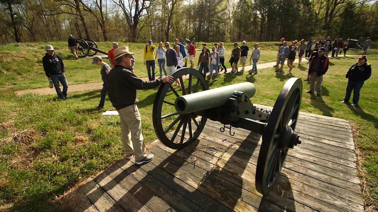  Civil war cannon on a platform with a group of people around it listening to a tour guide