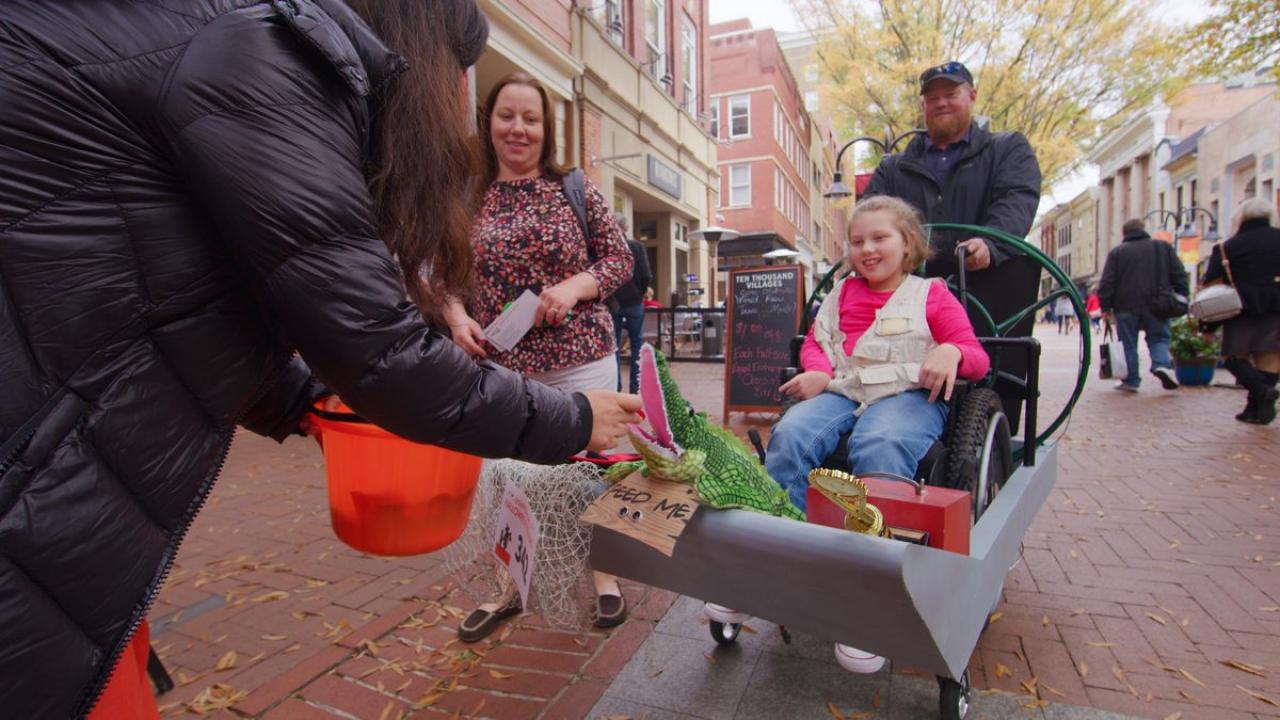 Child in a wheelchair trick or treating on the downtown Charlottesville mall
