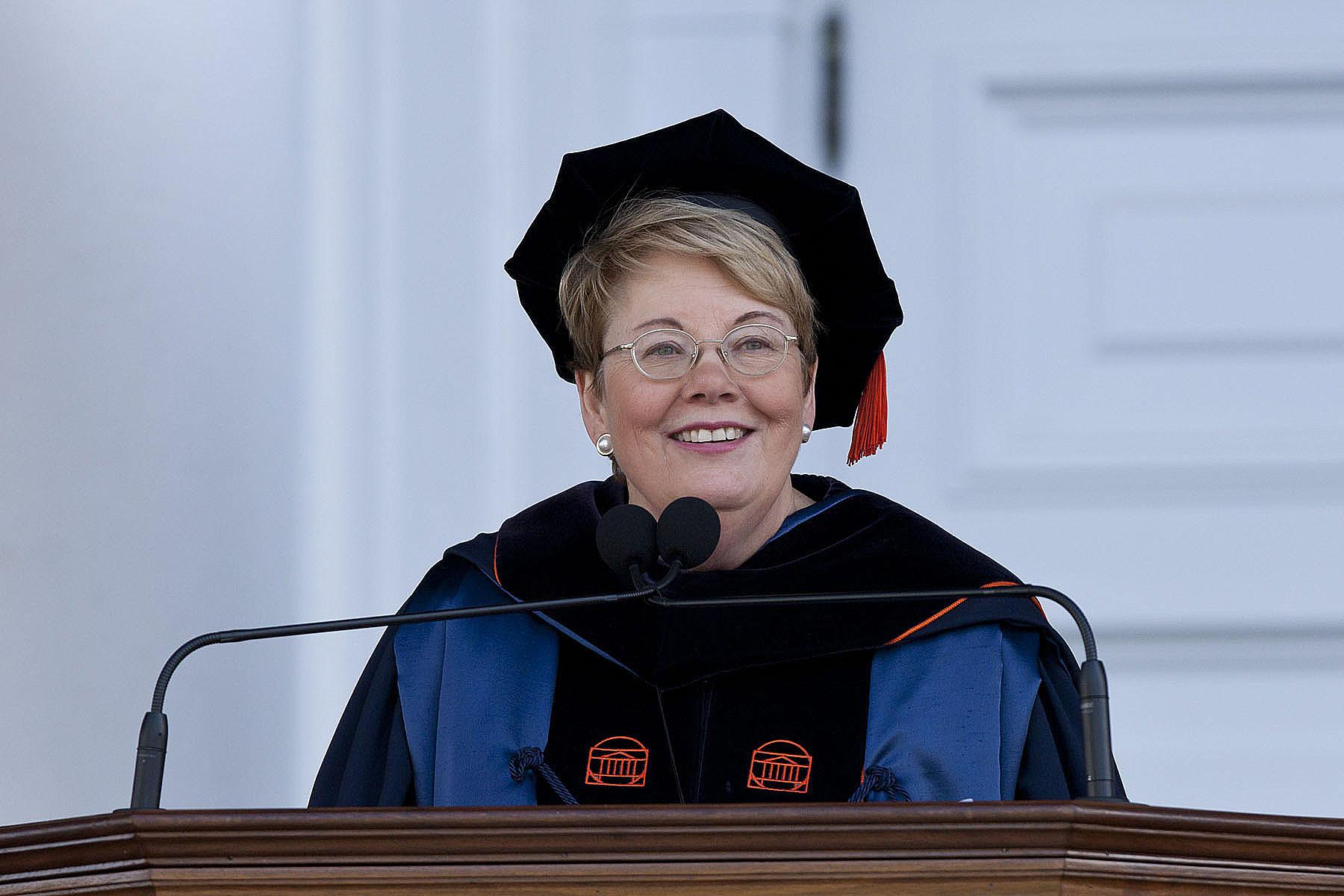 Teresa A. Sullivan dressed in graduation robe and hat speaking at a podium