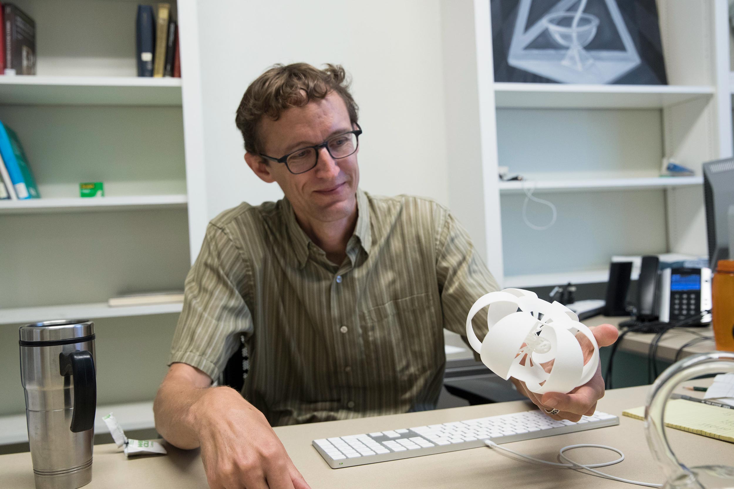 Thomas Mark, holding a 3-D-printed representation of a multi-dimensional shape, 
