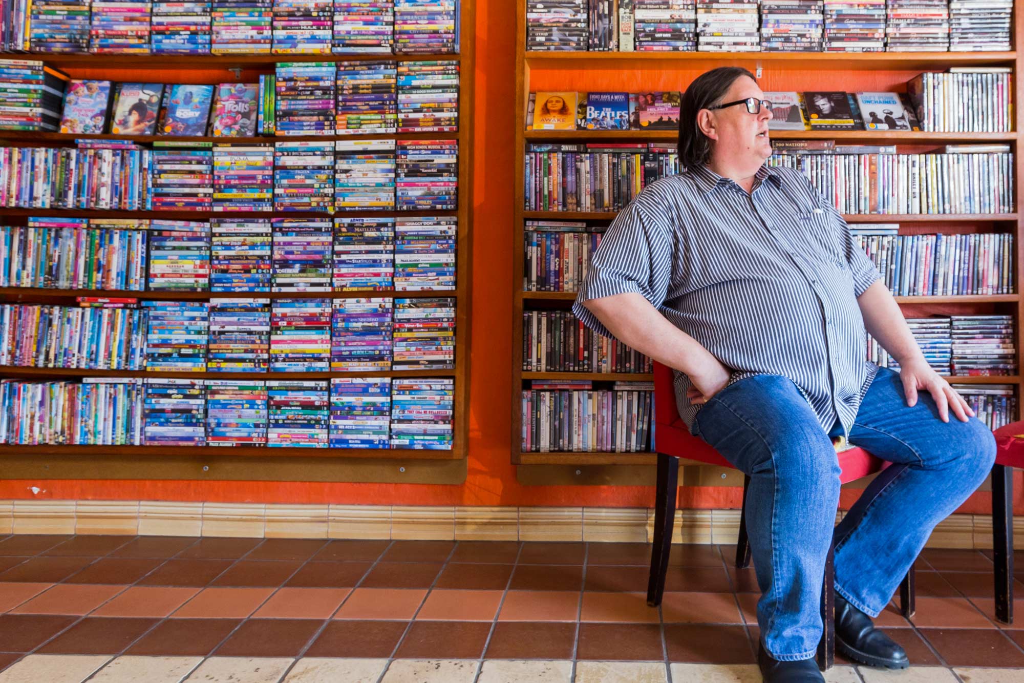 Man sitting in a chair with the wall behind them full of cds