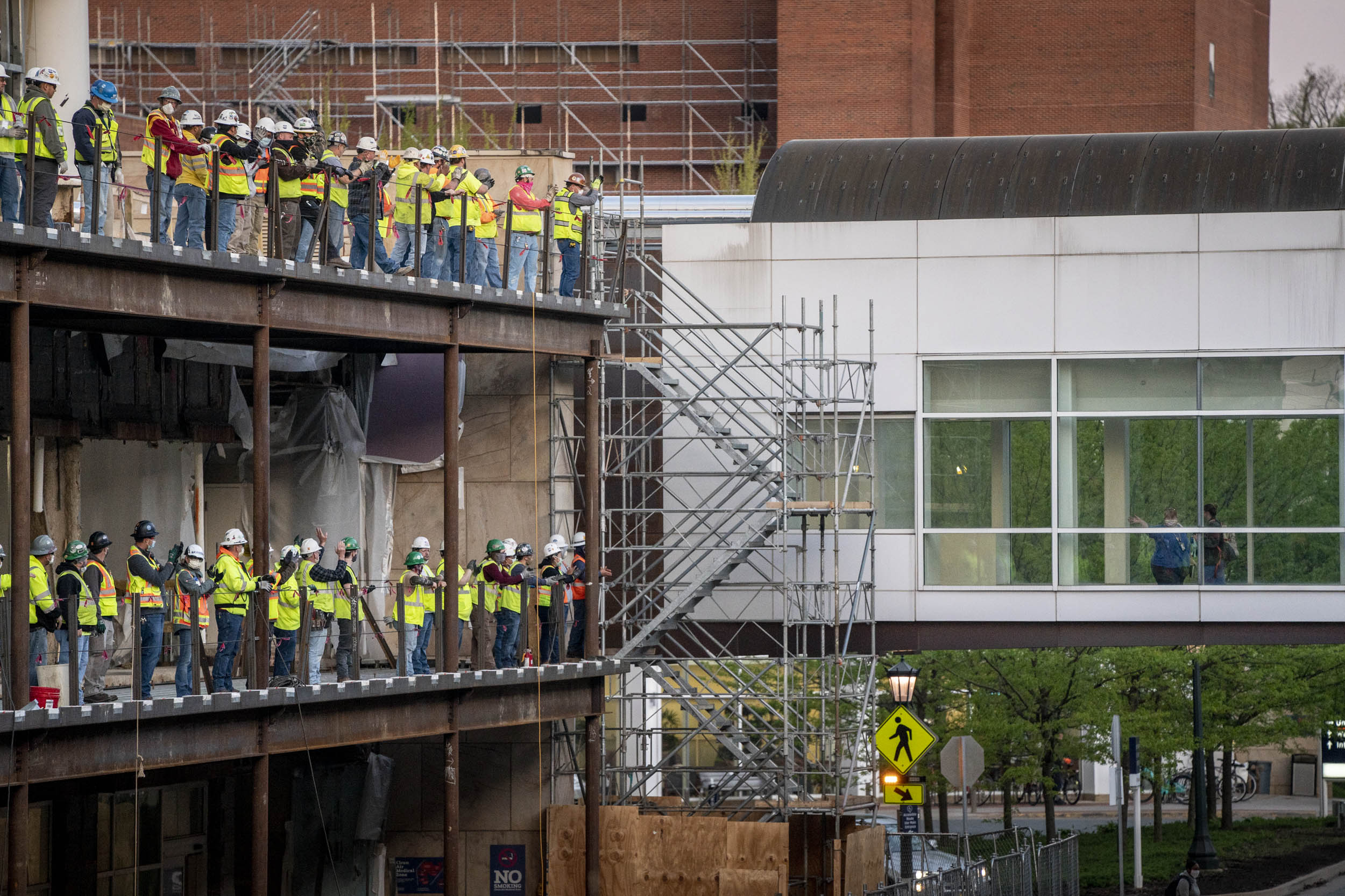 Construction workers lining the hospital construction project clapping as health care workers change shifts 
