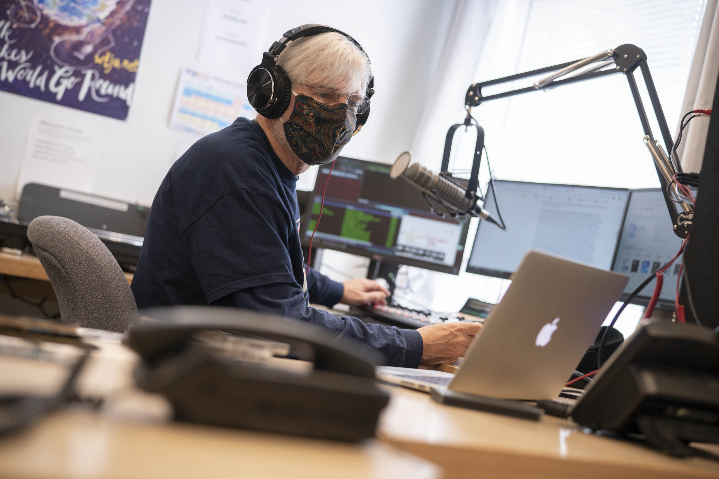 Person sitting at a desk looking at a laptop while running a radio show