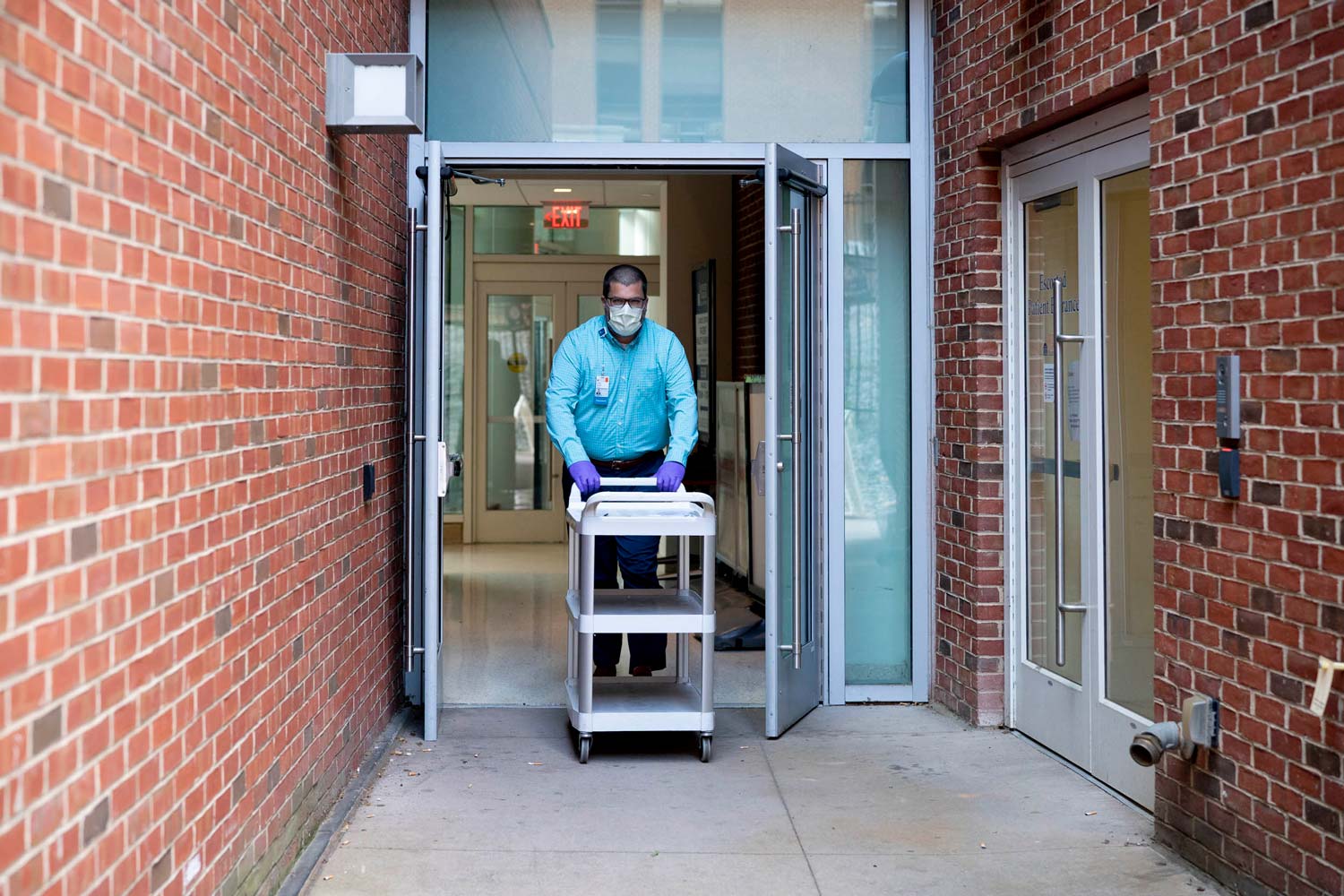 Man pushing a trolly outside of a building