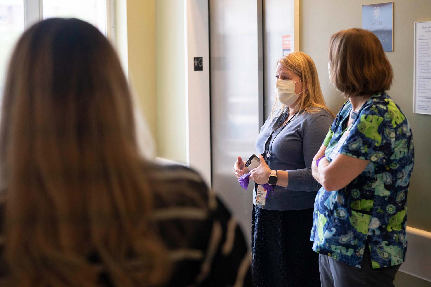 Nursing staff stand in a hallway having a meeting