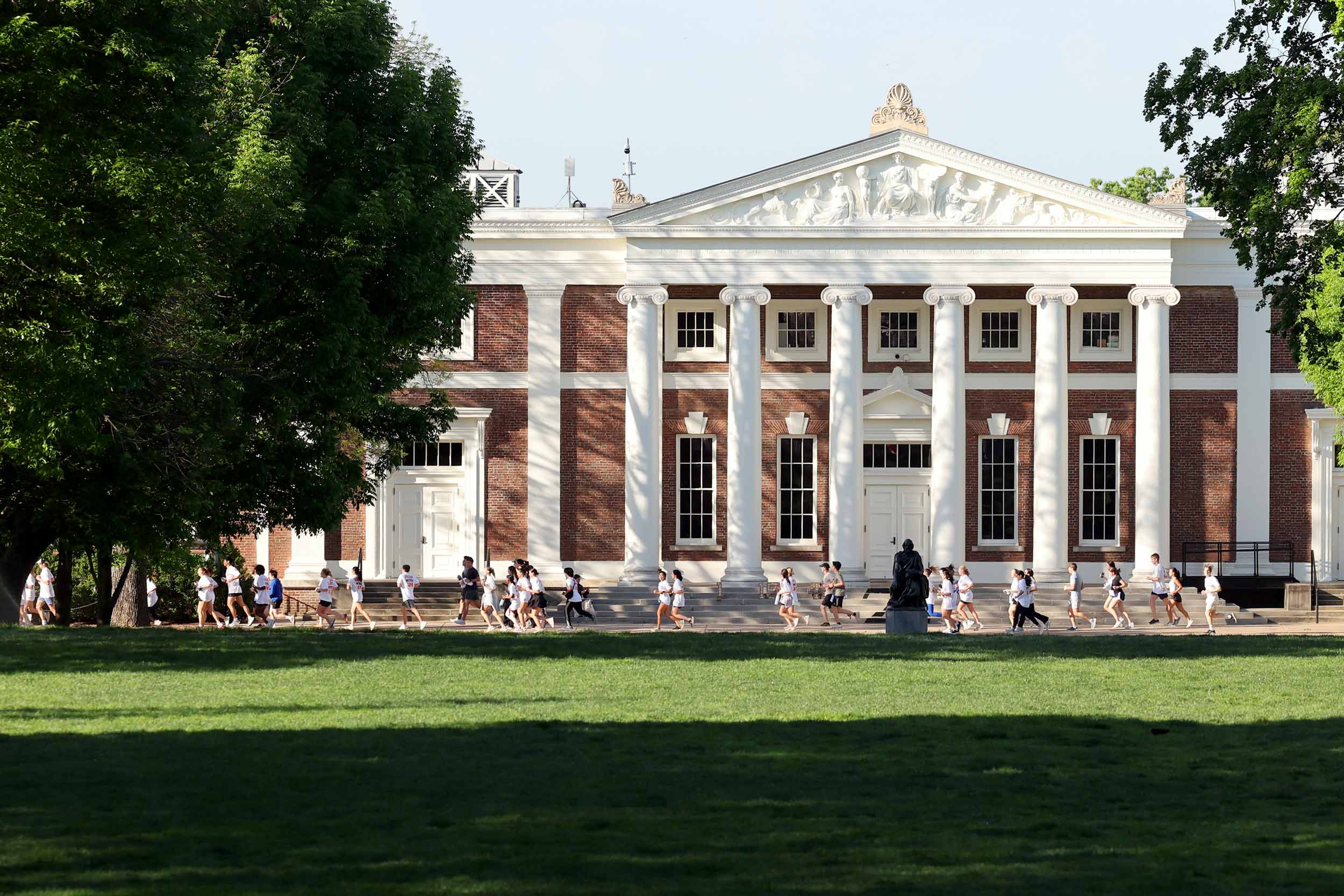 Picture shows a group of students running in front of UVA's Madison Hall.