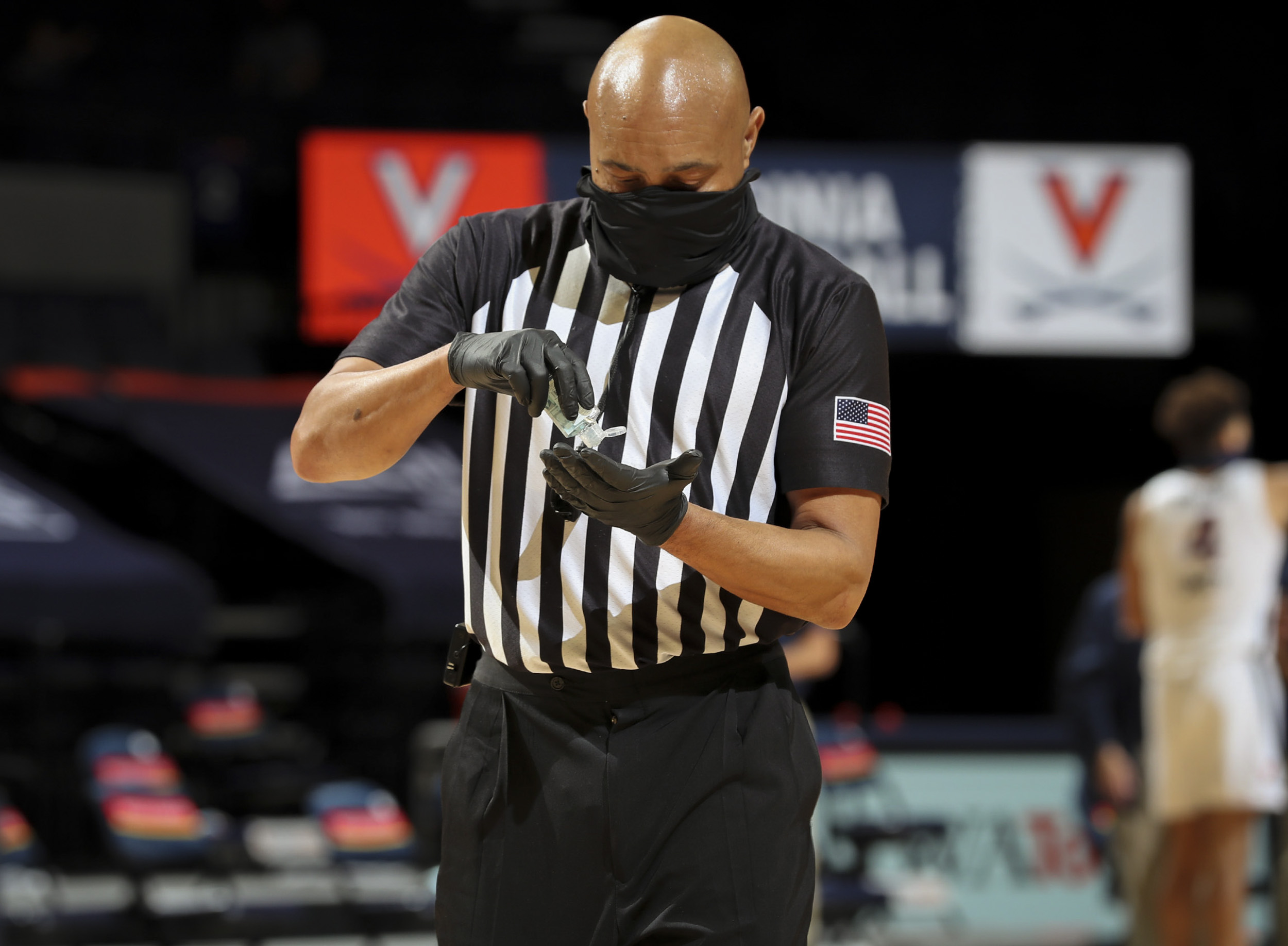 Basketball Referee sanitizing his gloves with hand sanitizer