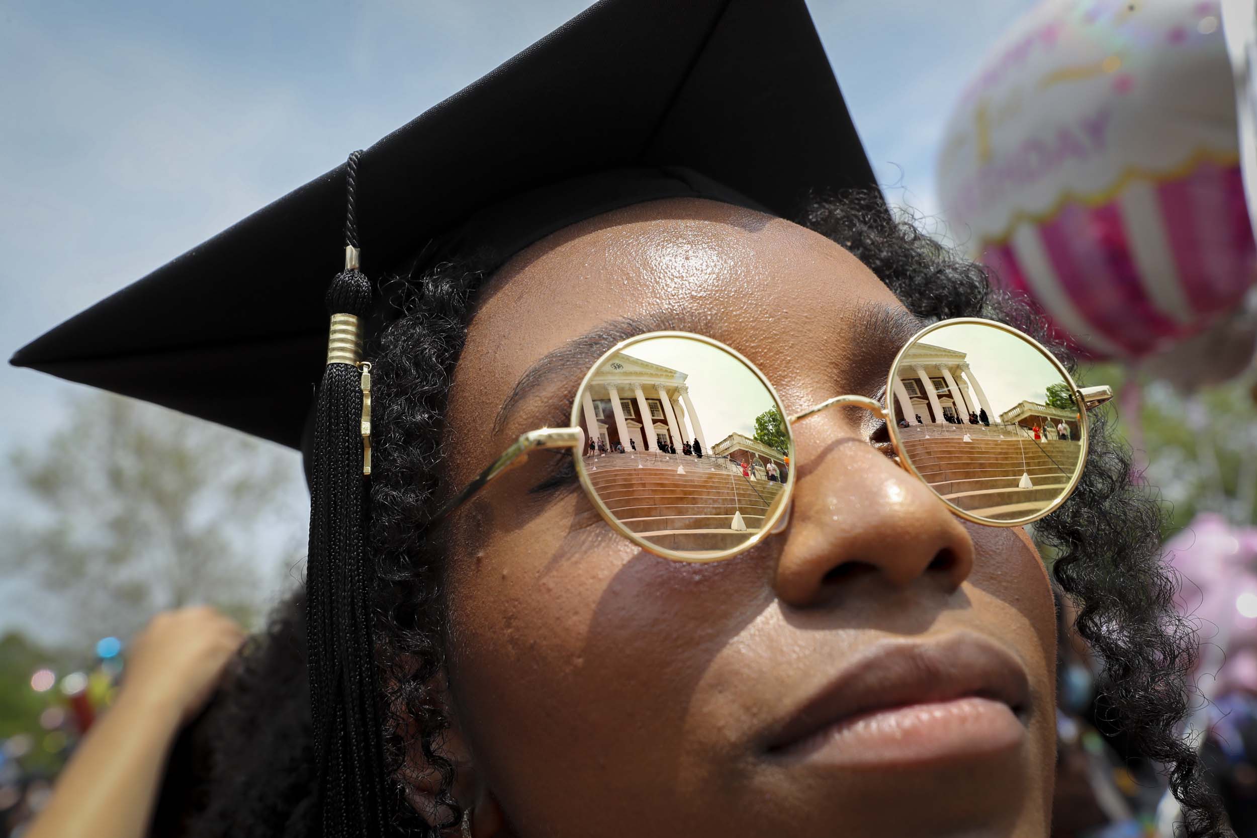 Up close of a graduates face with the reflection of the Rotunda in their glasses