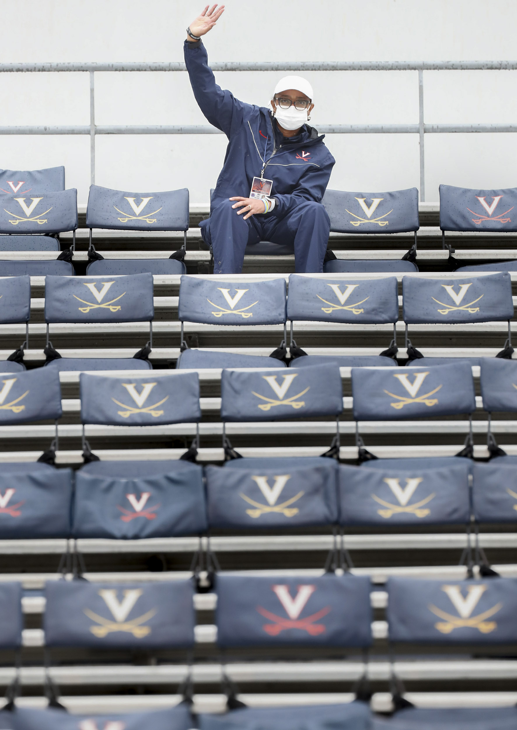 UVA Staff member sitting at the very top of the stands waving to the camera many rows down