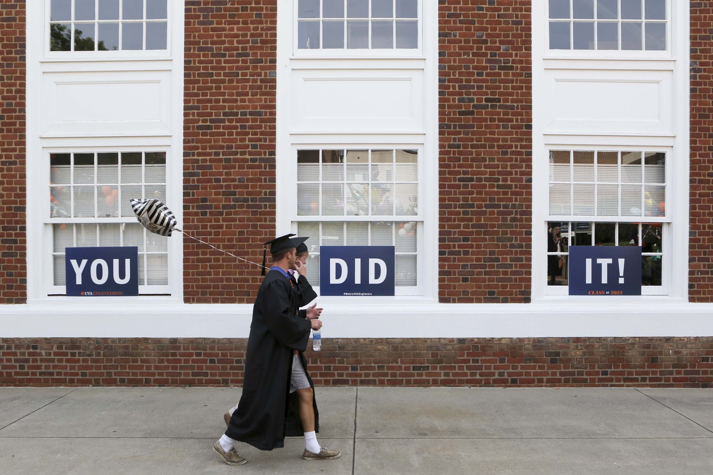 Two graduates walking past signs that read: You did it!