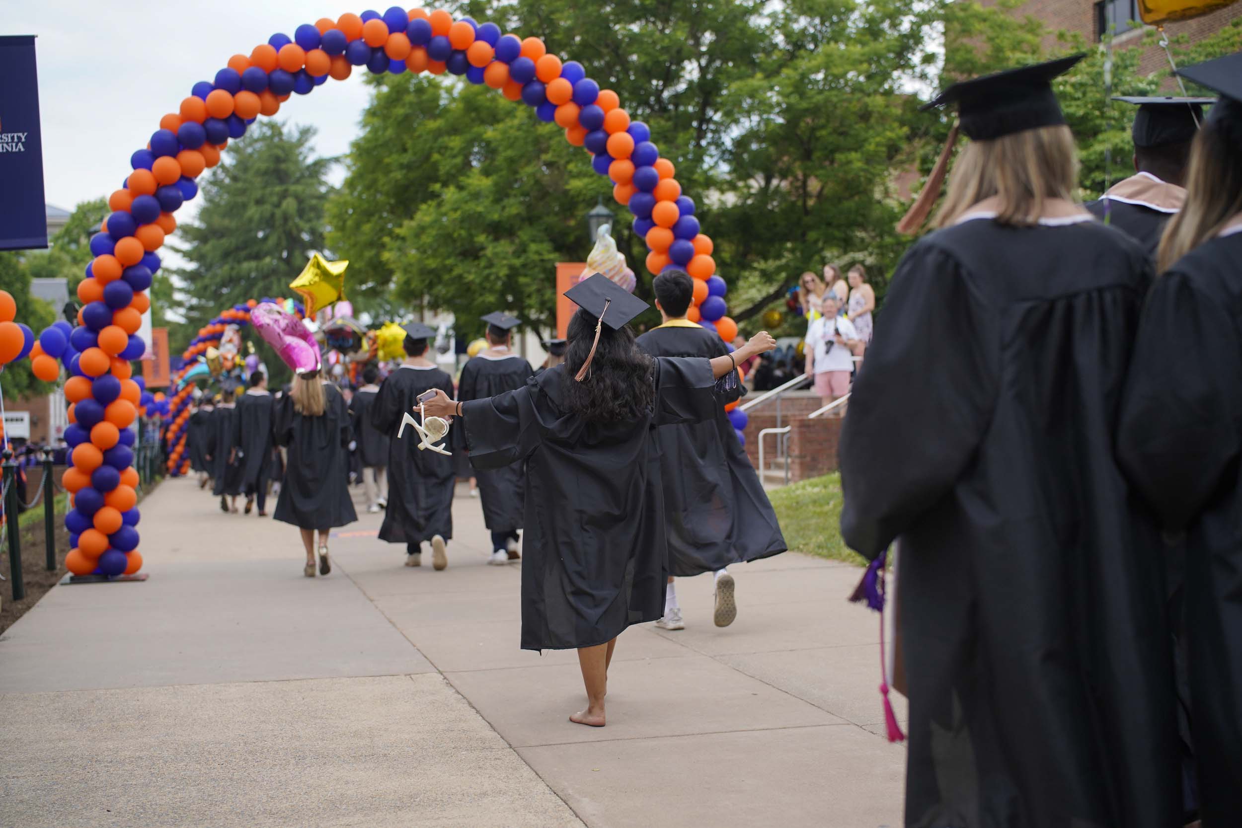 Graduates walking under blue and orange balloon arches
