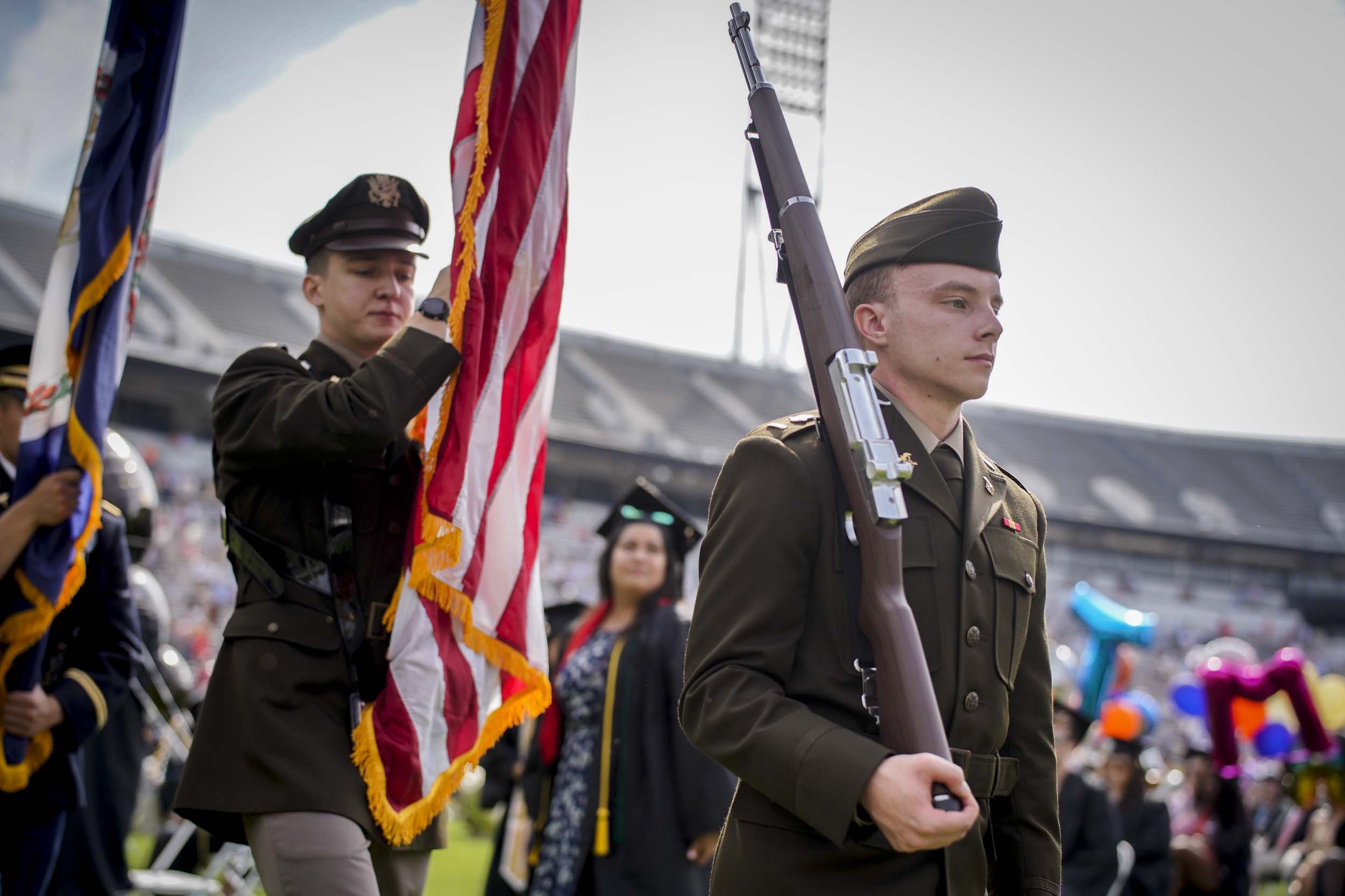 U.S. Color Guard walking in left to right: Color Guardsmen carrying the Virginia state flag, Color Guardsman carrying the United States of America Flag, Color Guardsman carrying a rifle on their right shoulder