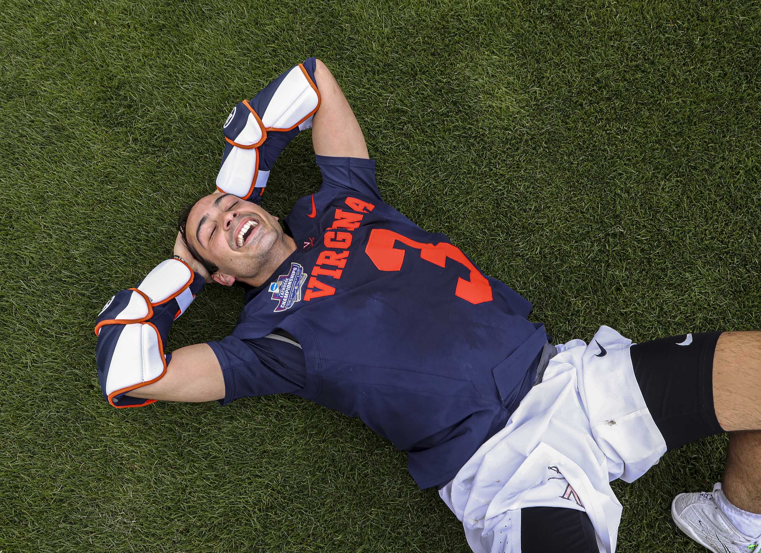 UVA player laying on the grass with arms above their head