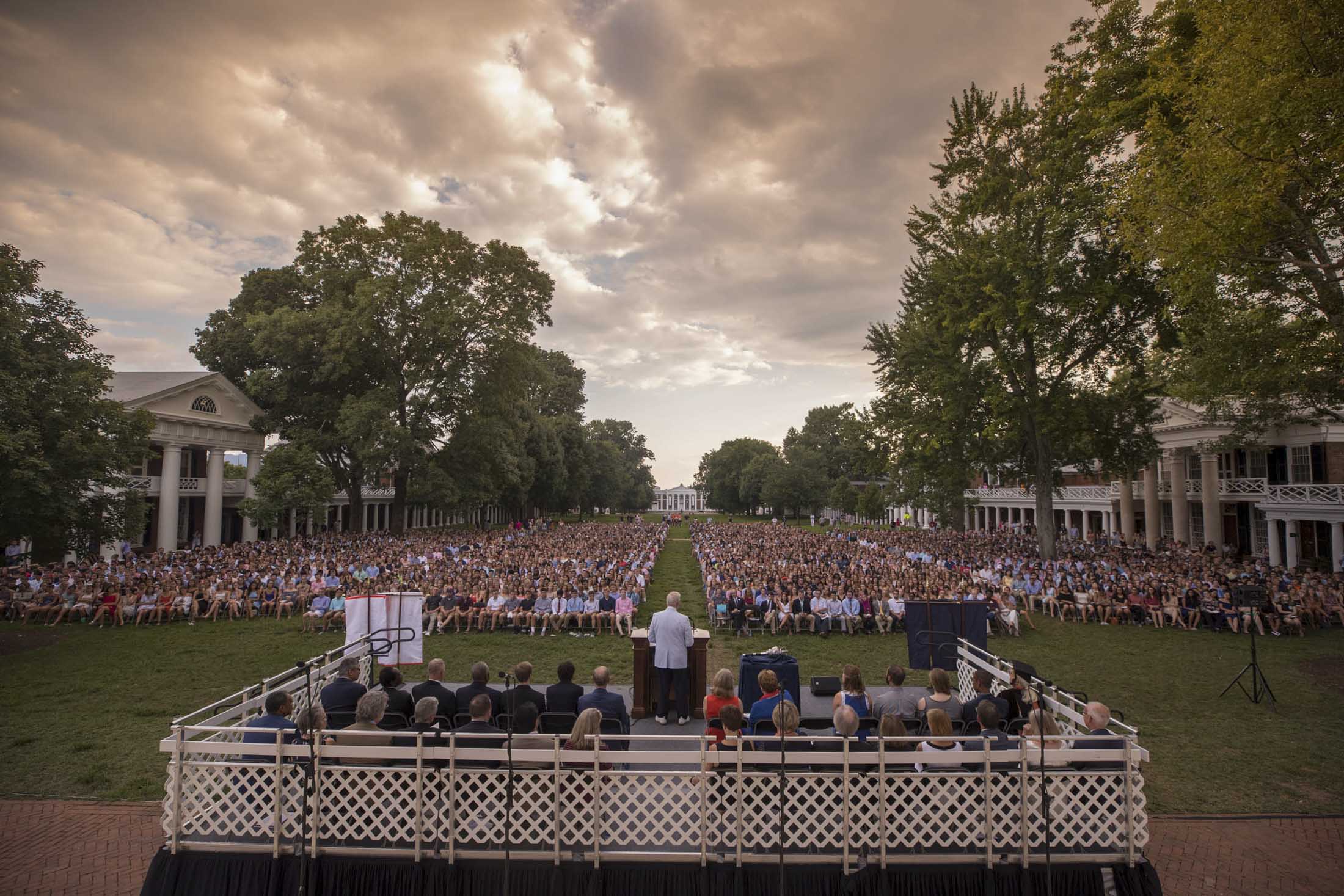 Students sit in chairs on the lawn listening to a convocation speaker