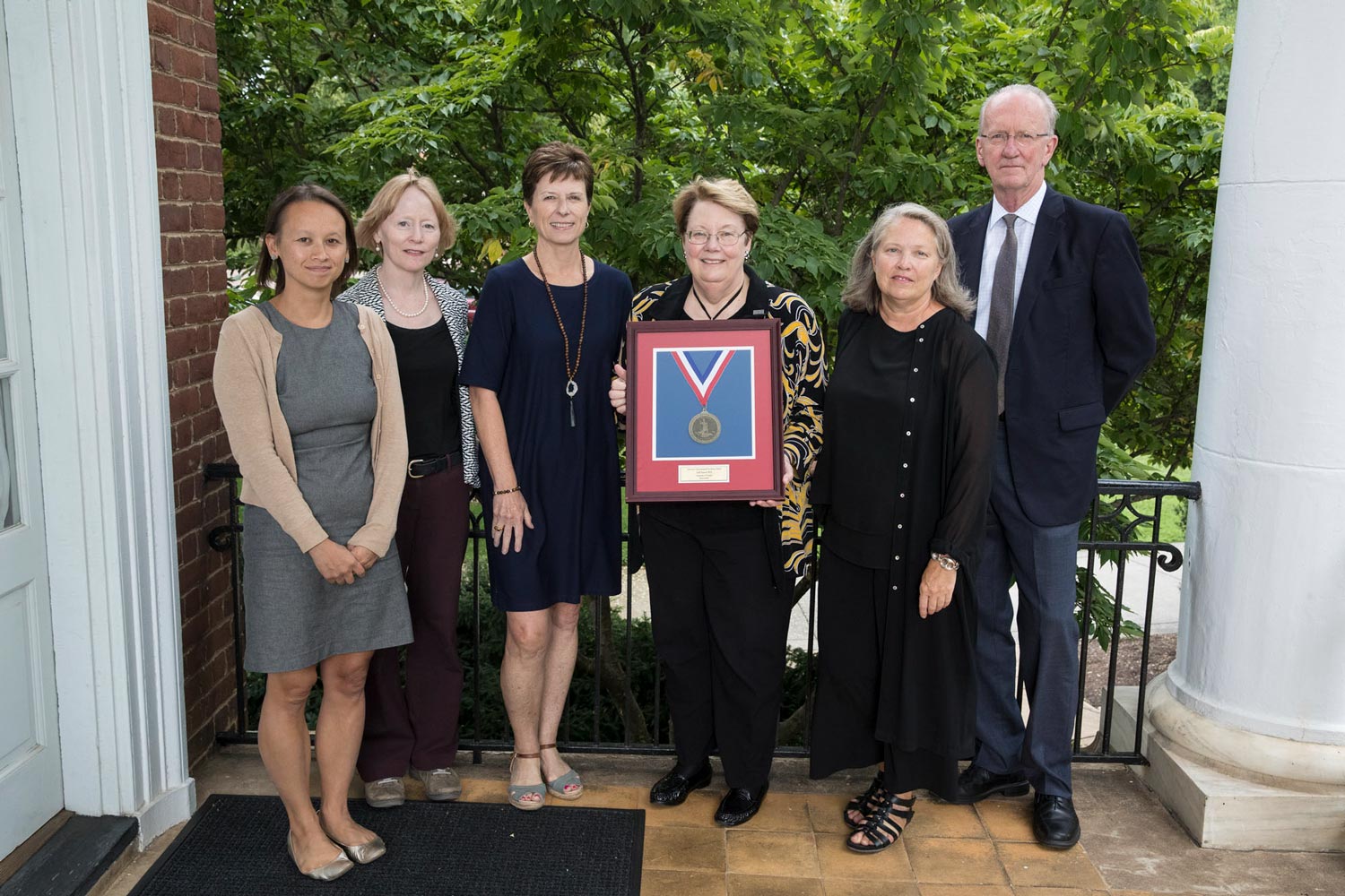 From left, Andrea Trimble, Cheryl Gomez, Colette Sheehy, Teresa A. Sullivan; Phoebe Crisman stand together for a picture while Sullivan holds a framed medal