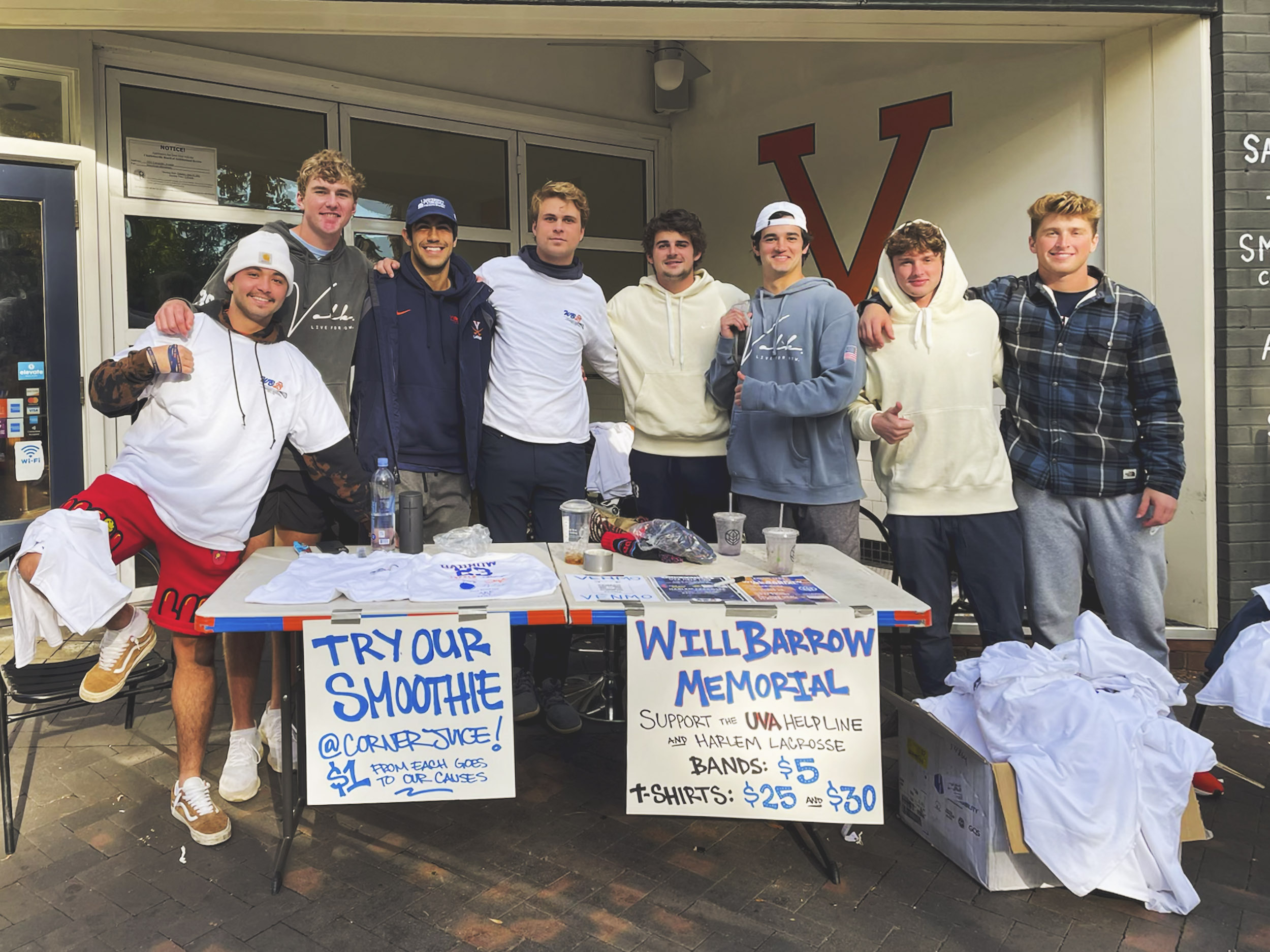 Group of students selling tshirts and smoothies at a table outside of a UVA building