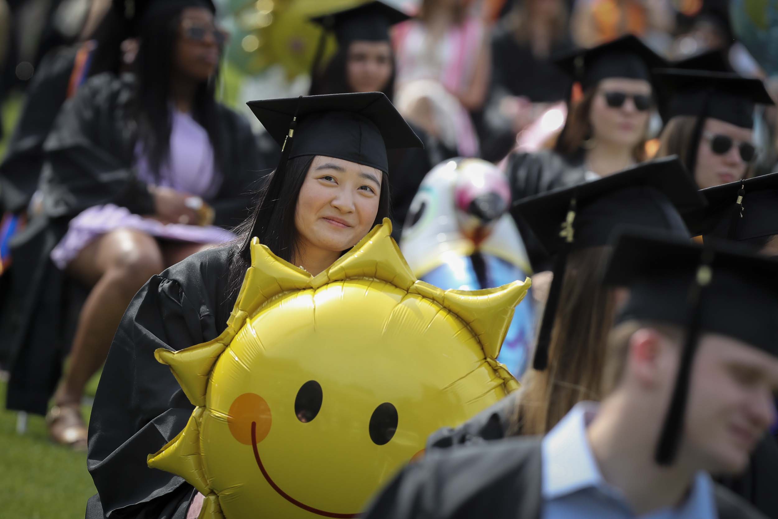 Graduate holding sun balloon 