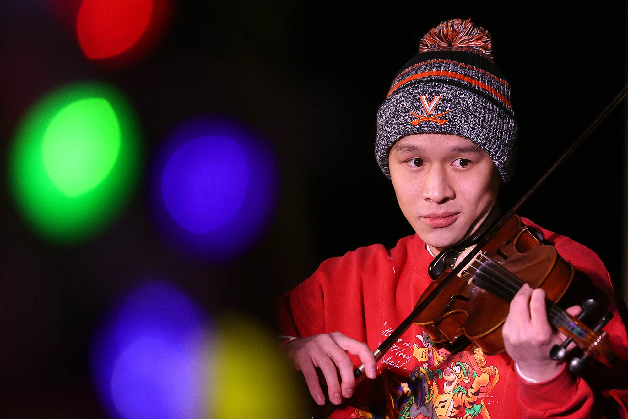 A student plays violin with holiday lights 