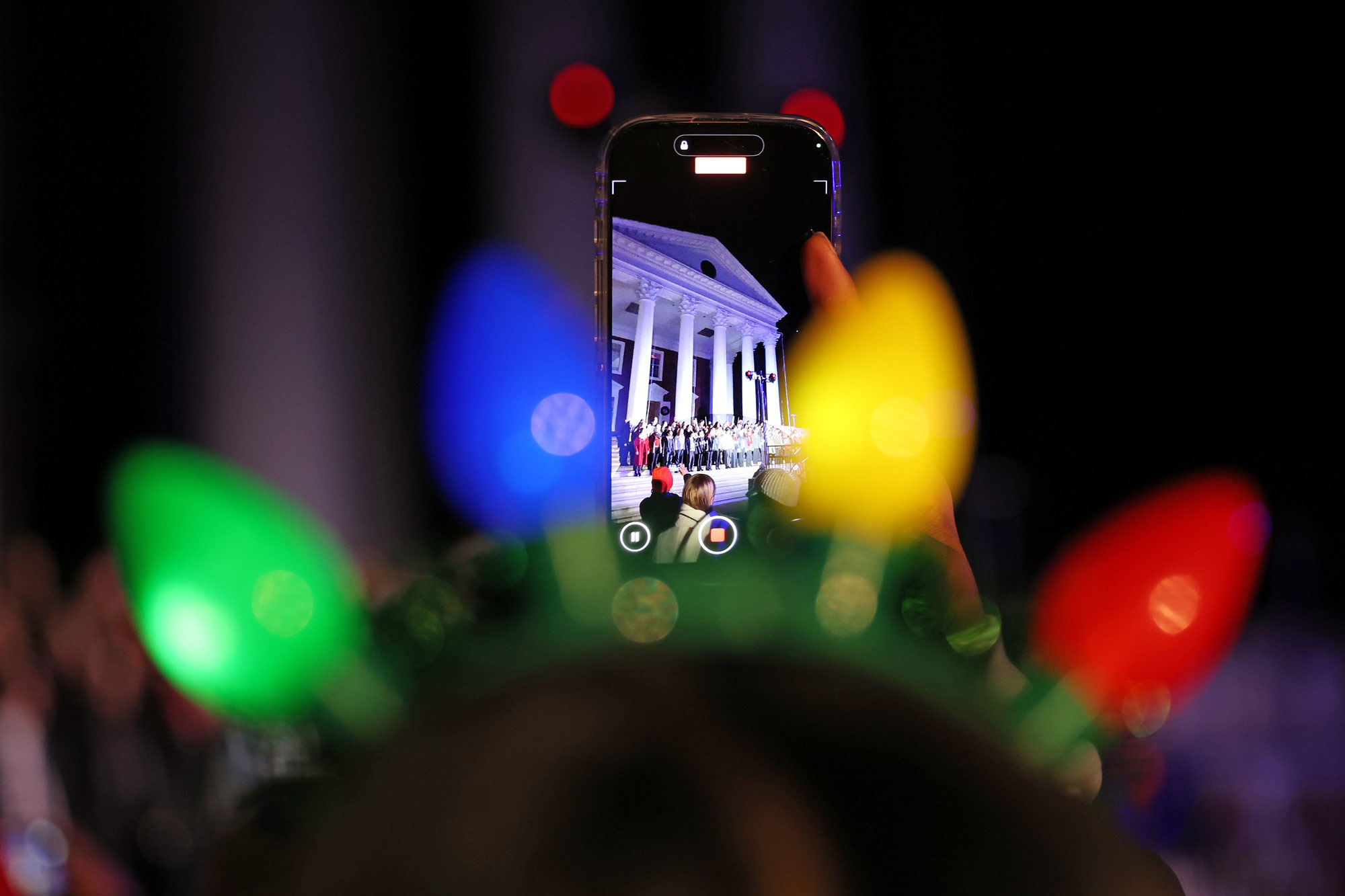 A student videos a performance at "Lighting of the Lawn" through the lights headband