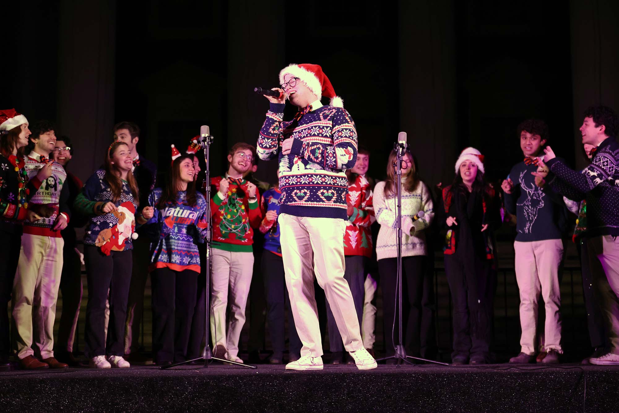 A lone singer steps out from the troupe in holiday sweaters