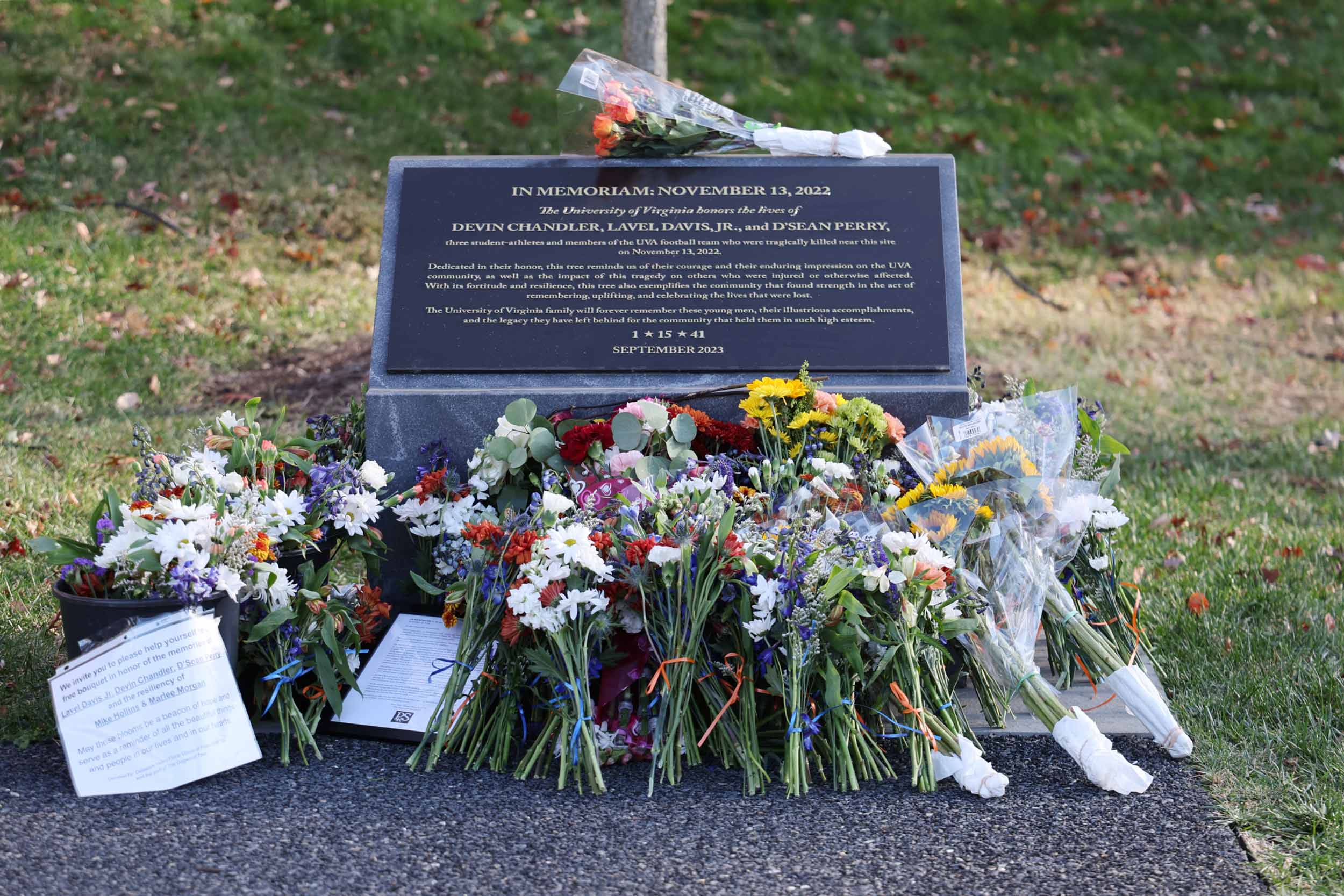 Close up of many bouquets of flowers laid at the base of the memorial to Devin Chandler, Lavel “Tyler” Davis Jr. and D’Sean Perry