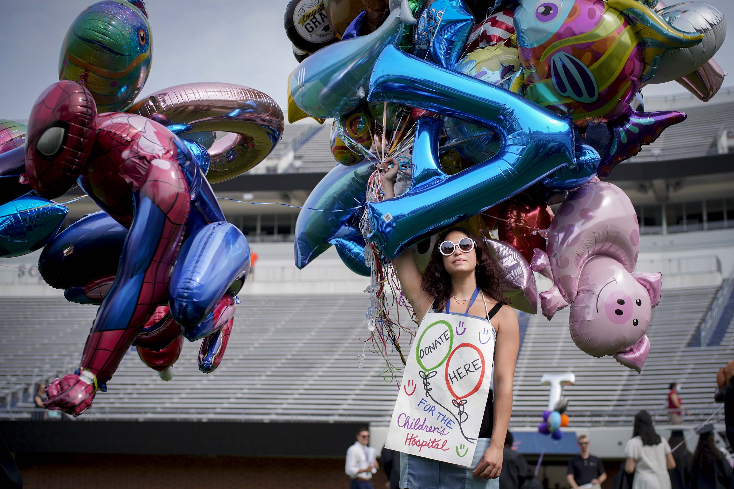 Woman holding balloons wearing a sign that reads: Donate here, for the Children's hospital