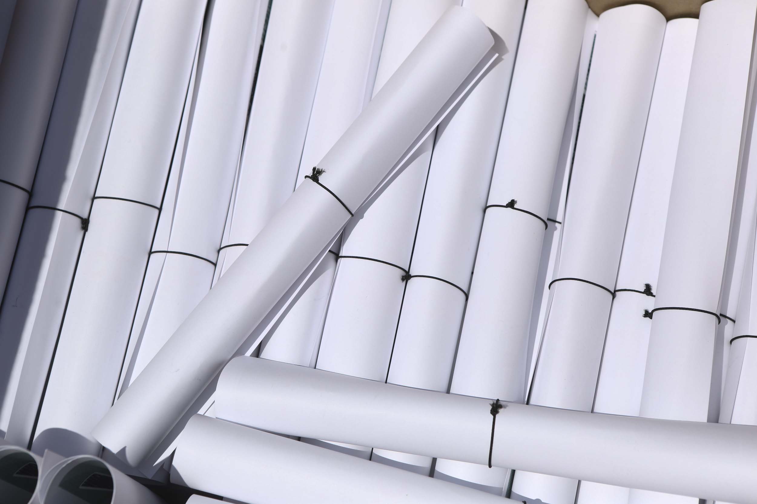 Rolled Diplomas in a stack with small black elastic bands keeping them each rolled up