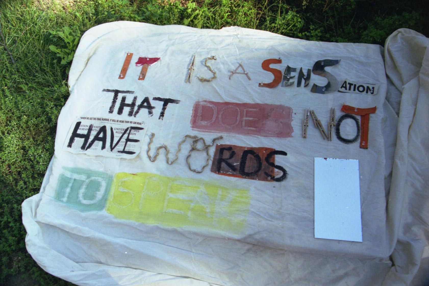 White sheet that has painted words that read: It is a sensation that does not have word to speak