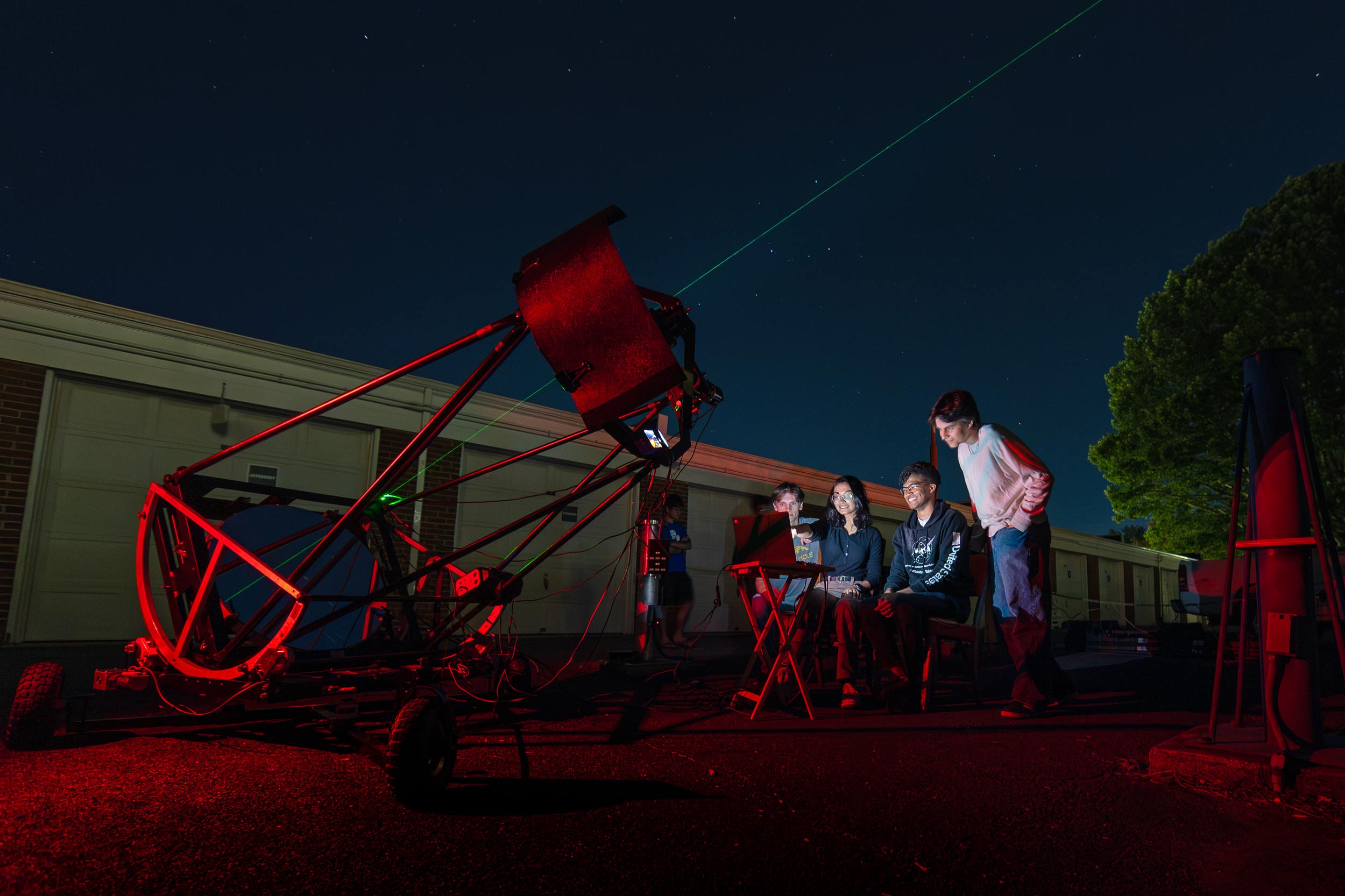 Portrait of Students in the Occultation Group monitor a computer screen while their telescope tracks an asteroid.