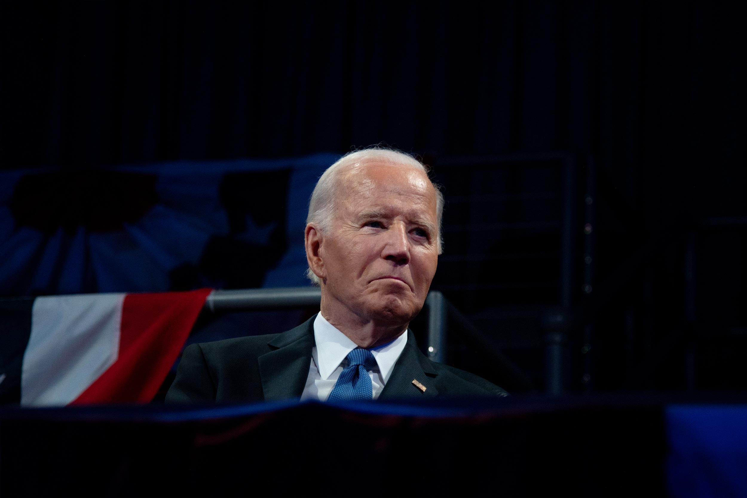 Former President Joe Biden sitting on stage at a conference