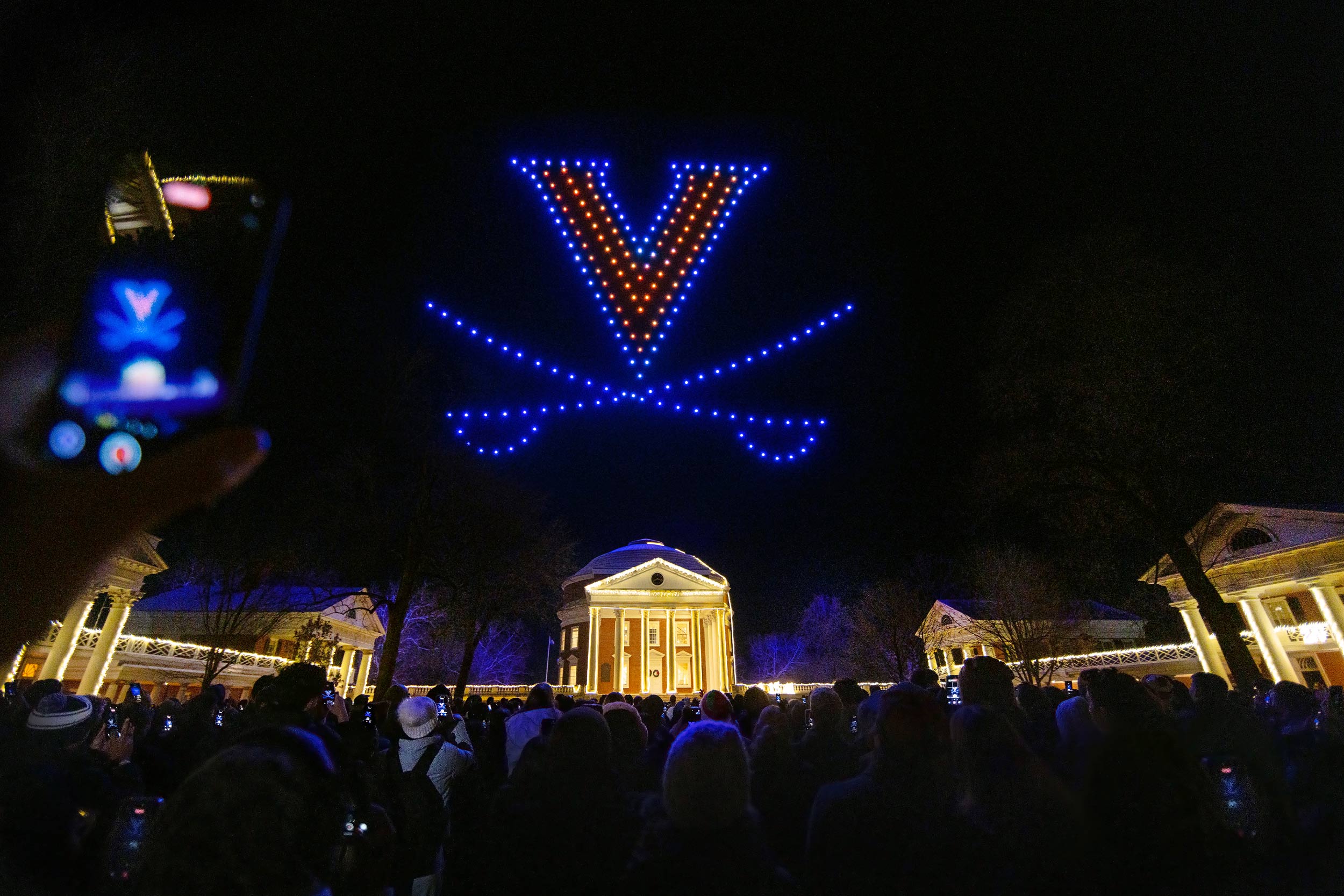 the UVA Rotunda lit at night with a drone light show over top in the formation of a ‘V-Saber’