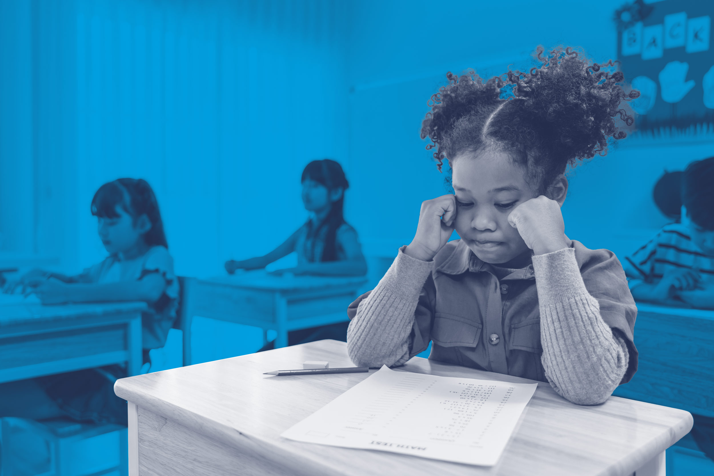 Children sit at their desks looking tired