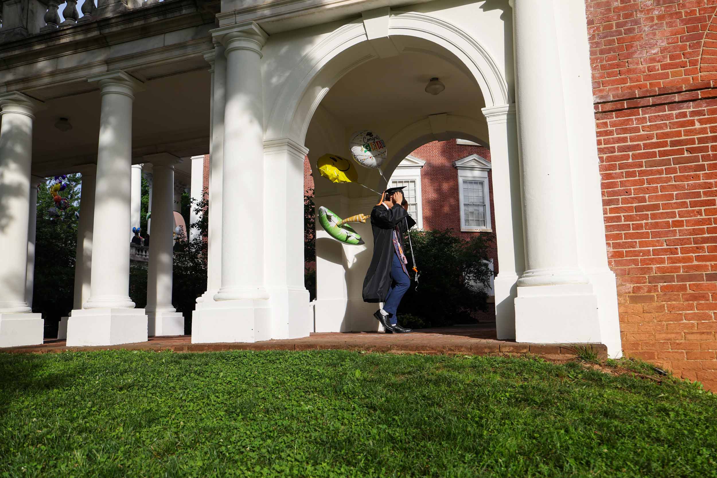 A graduate adjusts their mortarboard as they walk over to the Rotunda to line up for Final Exercises 2025
