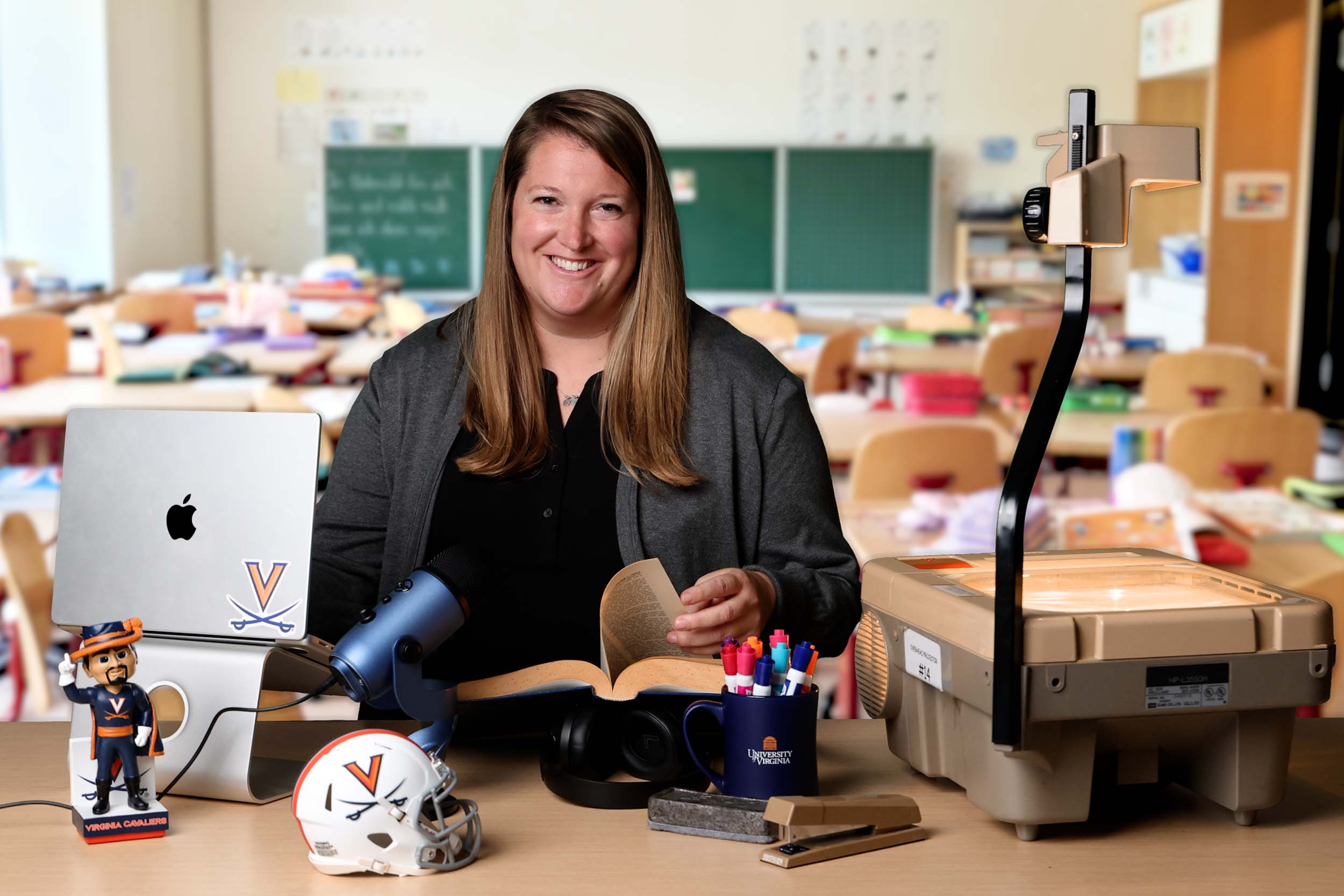 Anne Jewett sitting at her desk with a virtual classroom background