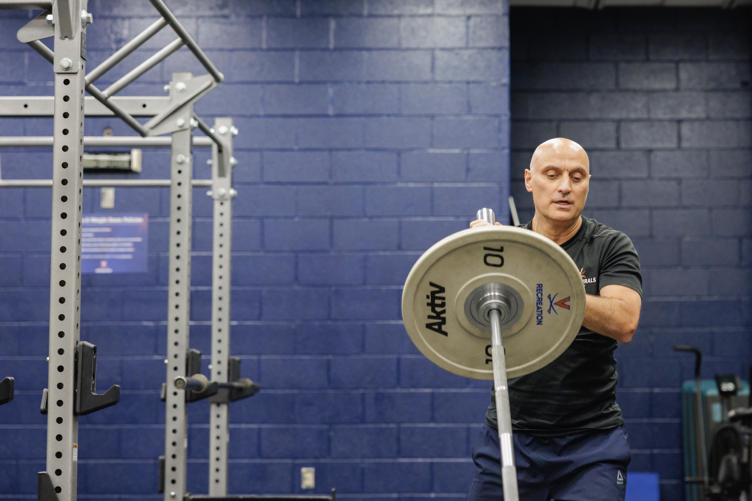 Hamid “Jim” Karimi putting a large weight on a bar at the North Grounds Recreation Center