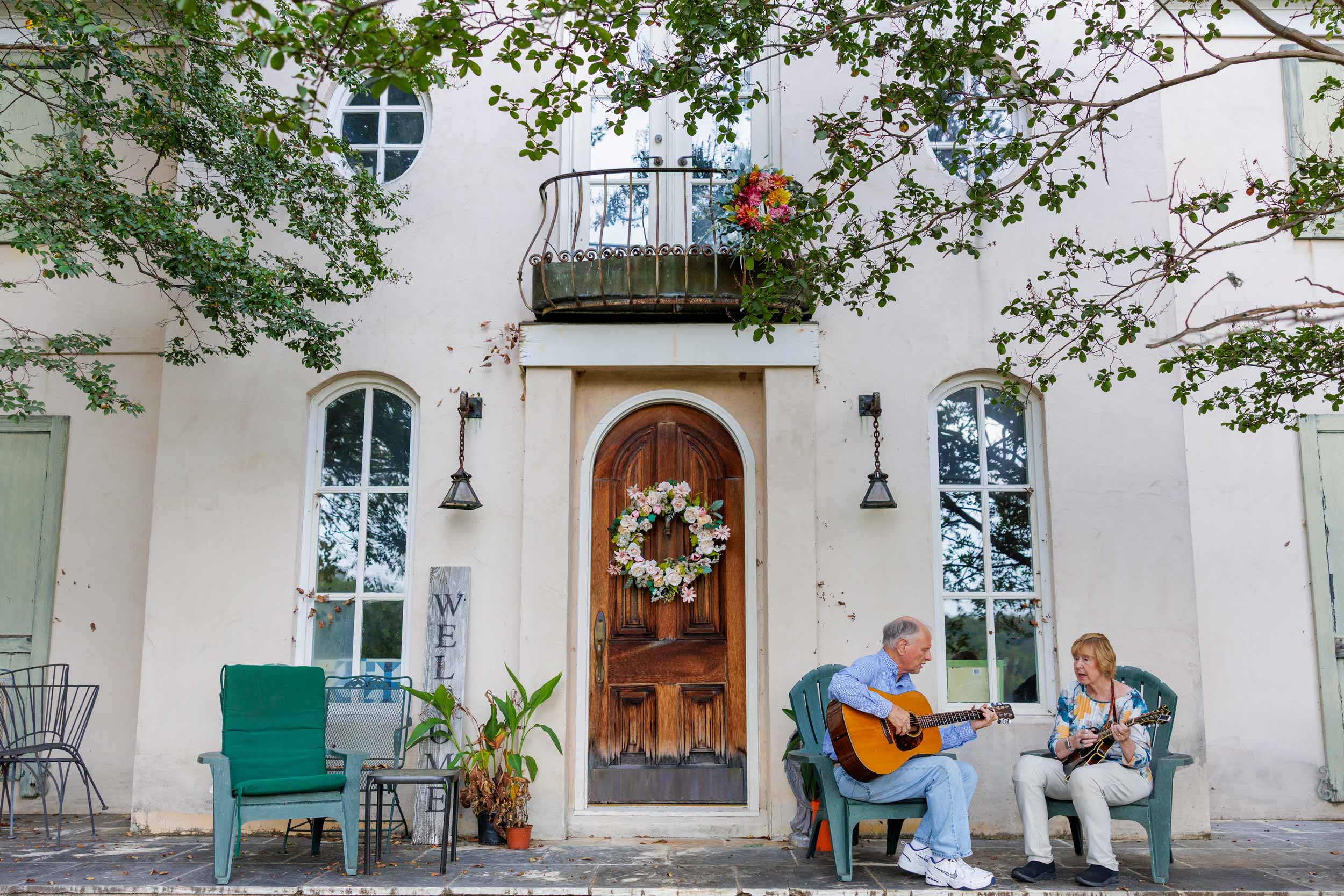 Dr. JoAnn Pinkerton and Alan Pinkerton sit outside the front door of their home playing mandolin and guitar