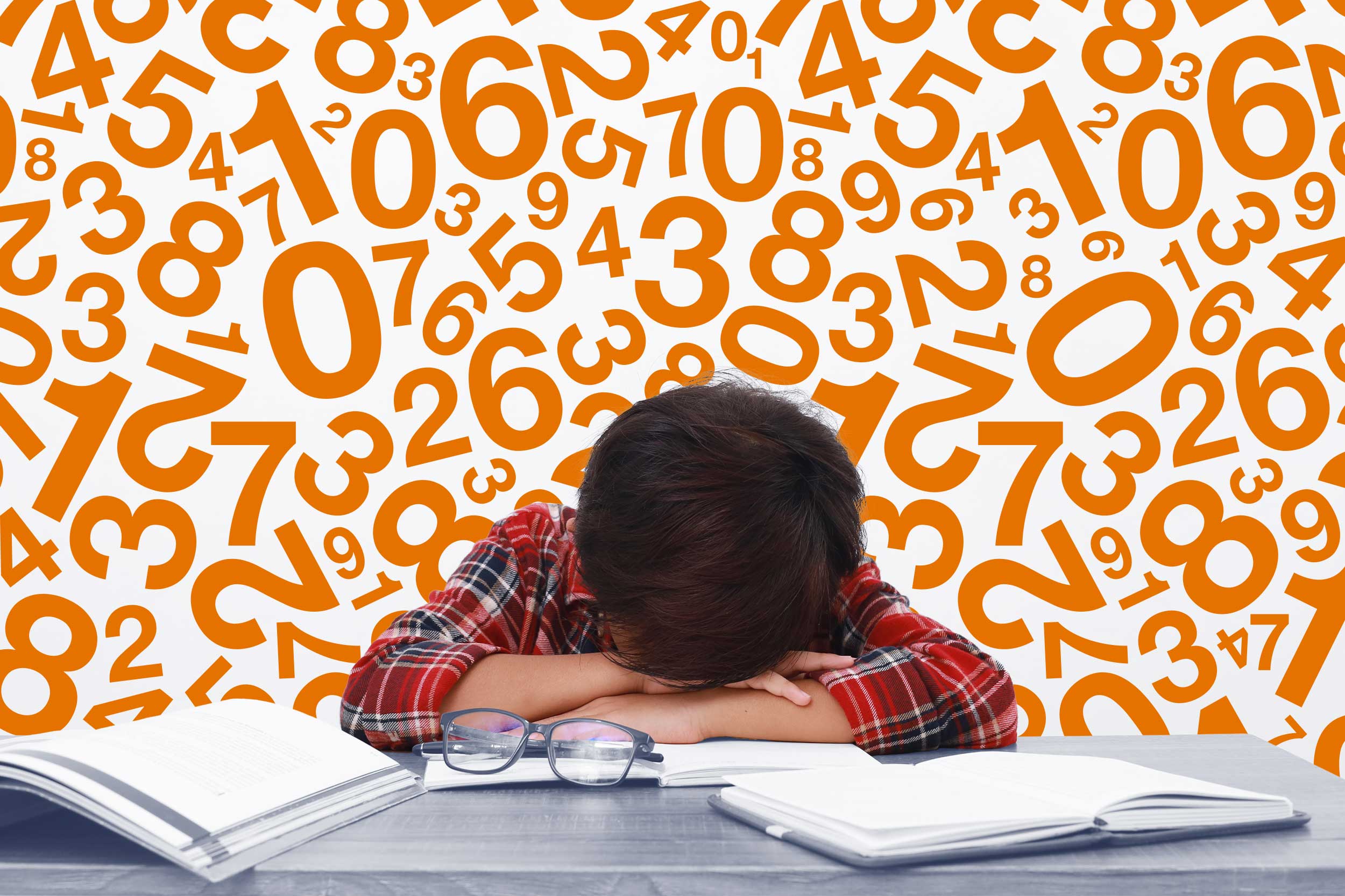 student laying head on desk surrounded by numbers and books