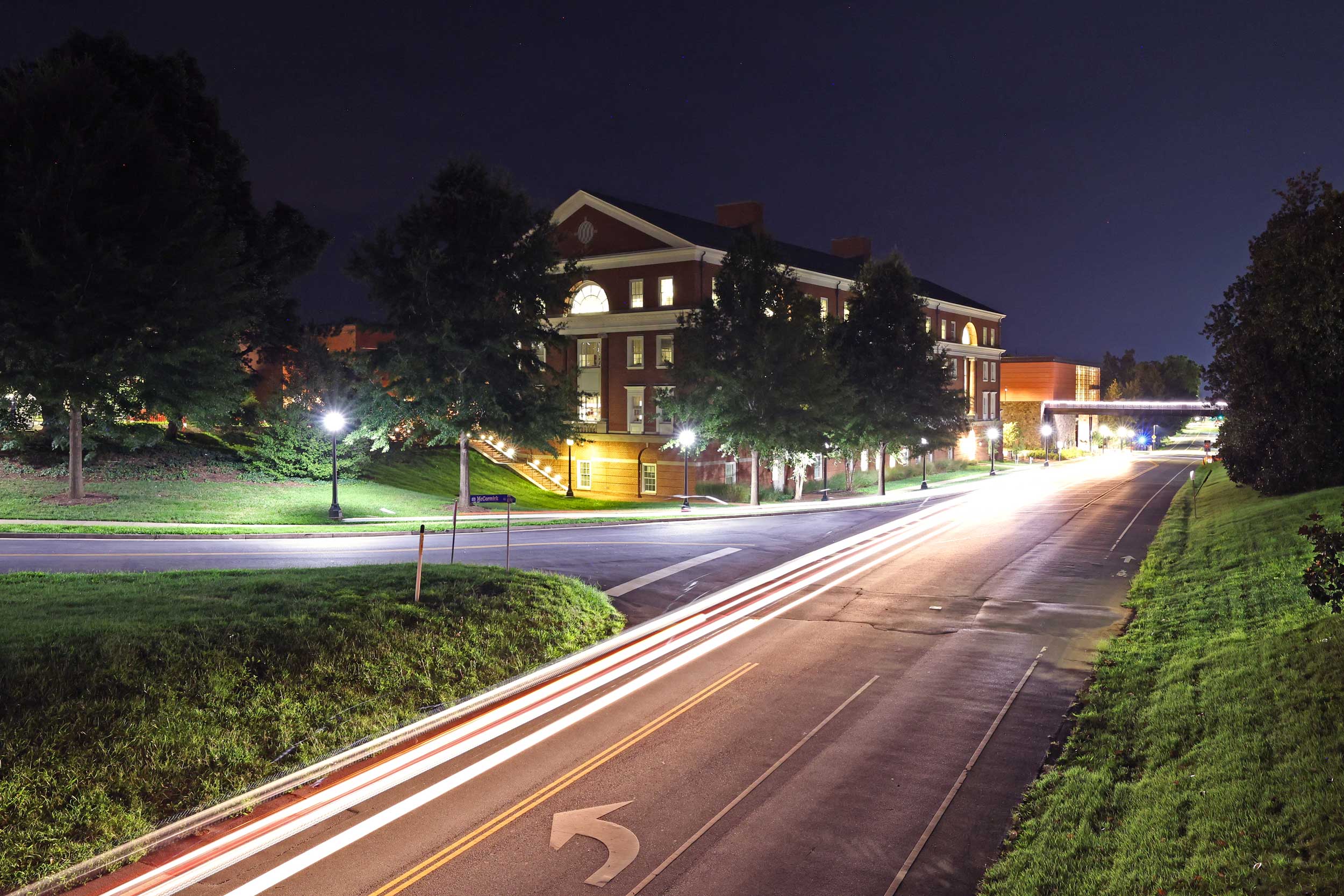 Portrait of a road in front of the UVA School of Education building, glimmering at night.