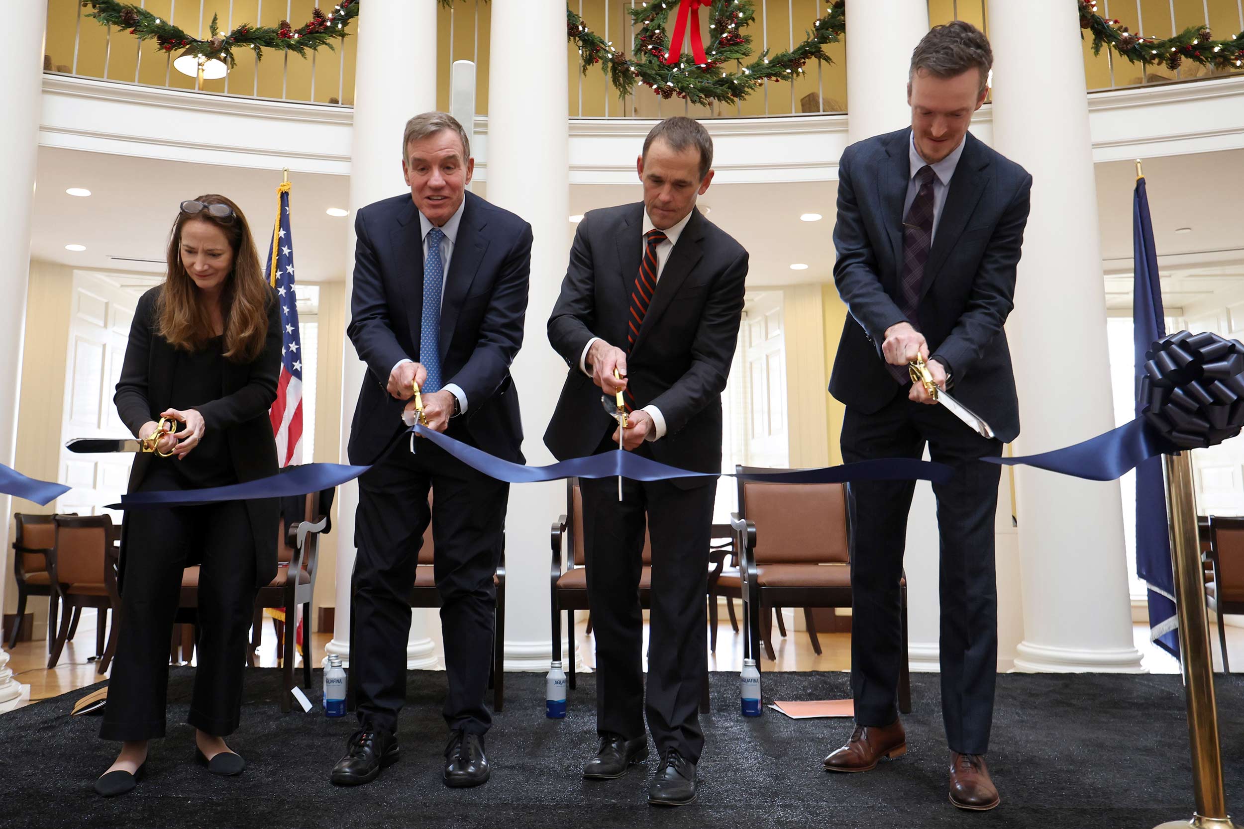 Candid photo of Avril Haines, Mark Warner, Jim Ryan and Philip Potter cutting a ceremonial ribbon