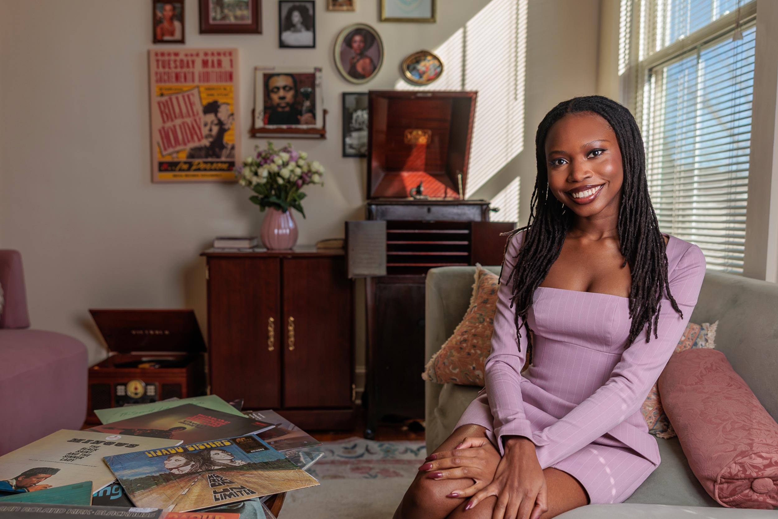 Omonye Isi sitting in her living room in front of a vintage Hi-Fi with several vinyl records on the coffee table.