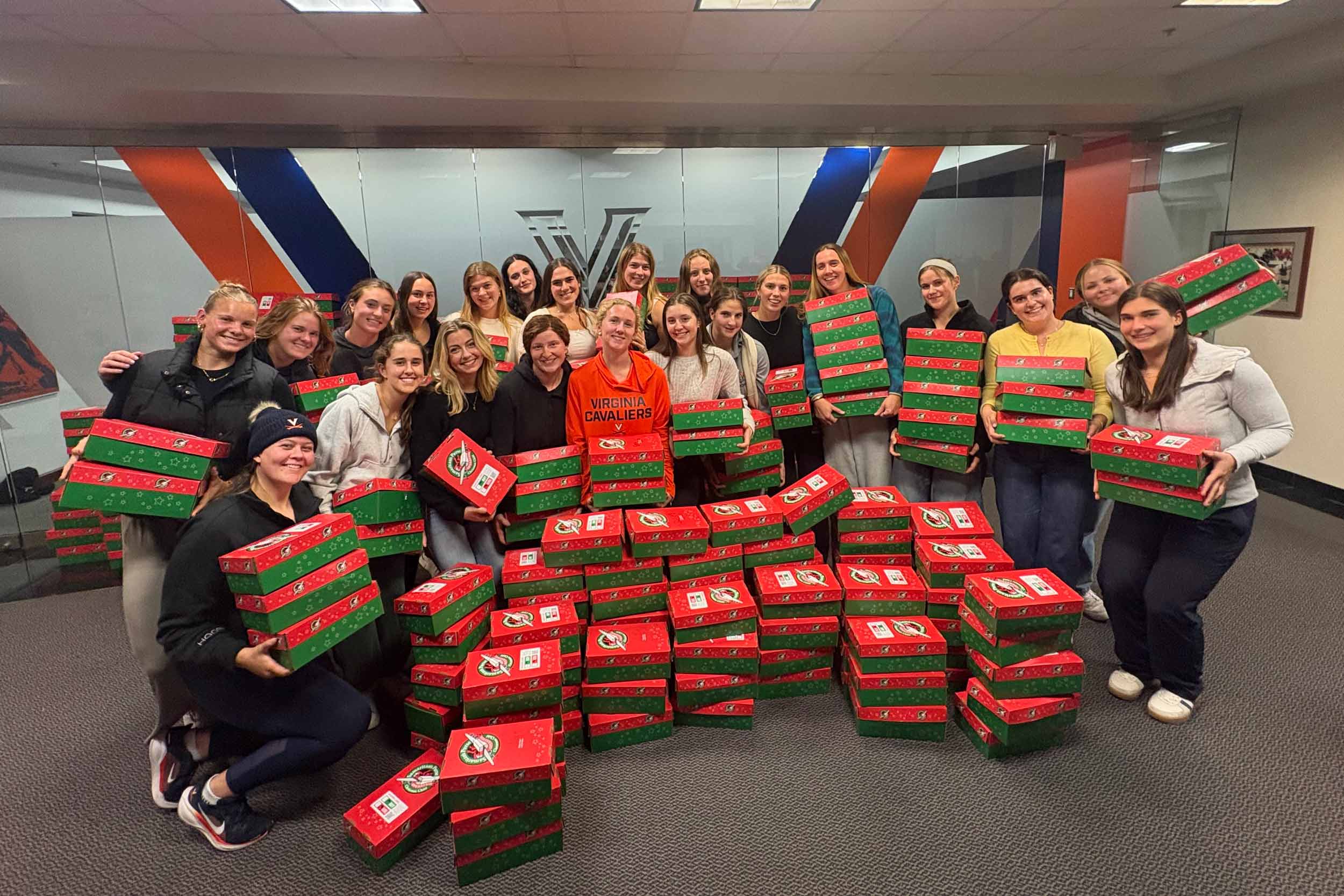 the UVA women's rowing team posing for a photograph behind 133 shoeboxes.