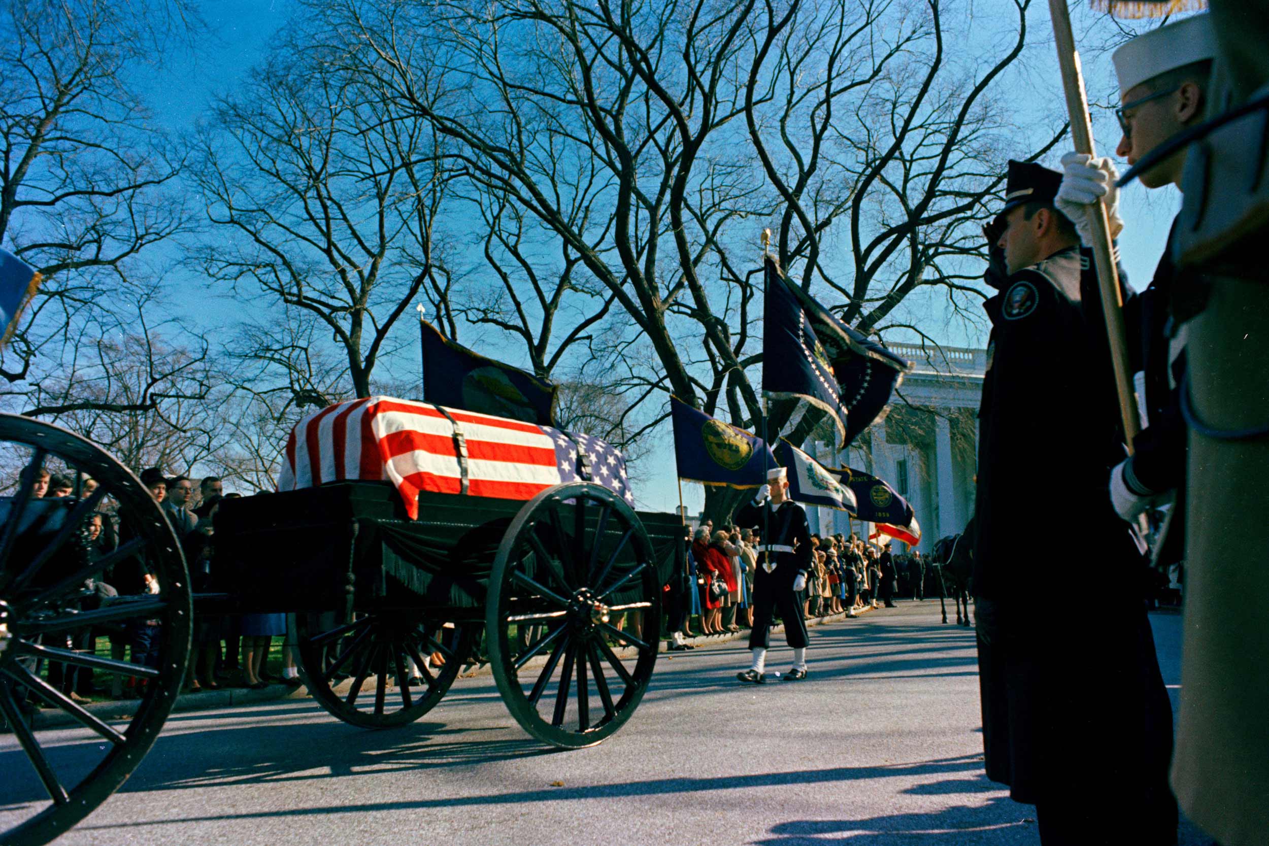 Flanked by a military honor guard, slain President John F. Kennedy’s flag-draped casket  