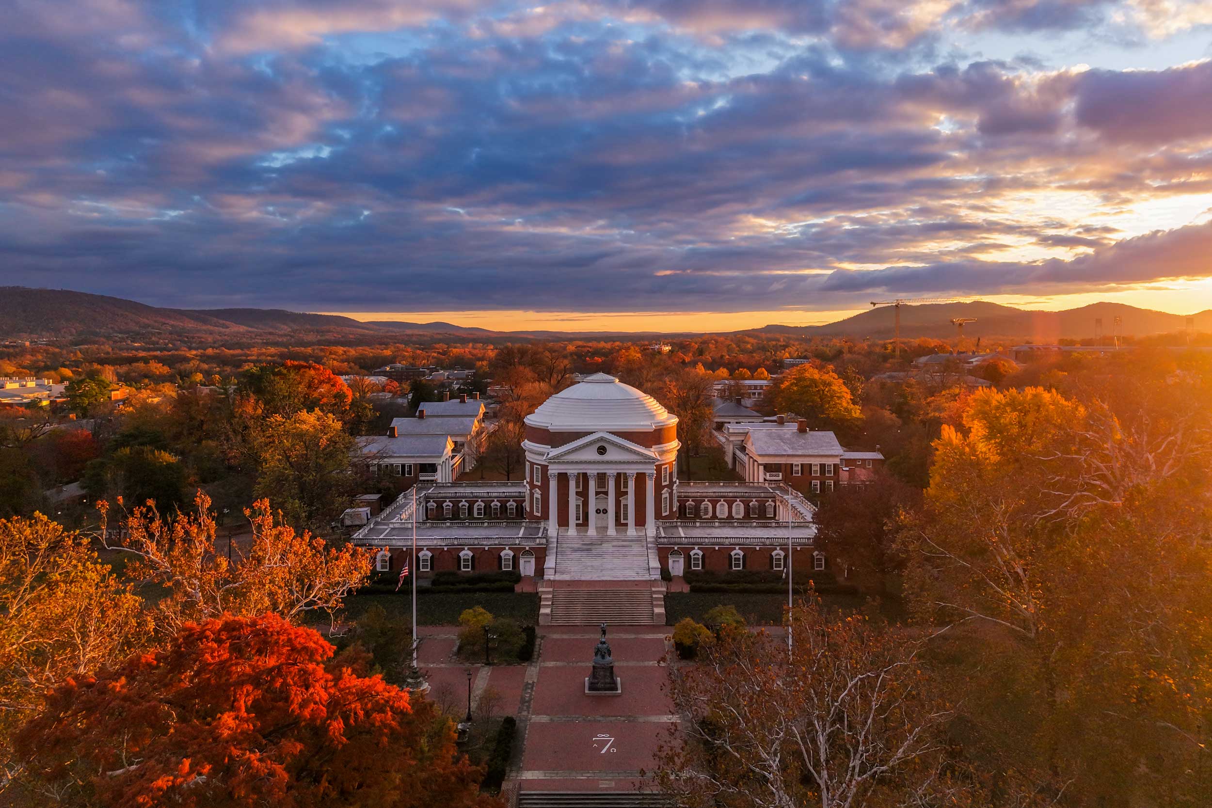 the UVA Rotunda at sunset surrounded by fall foliage.