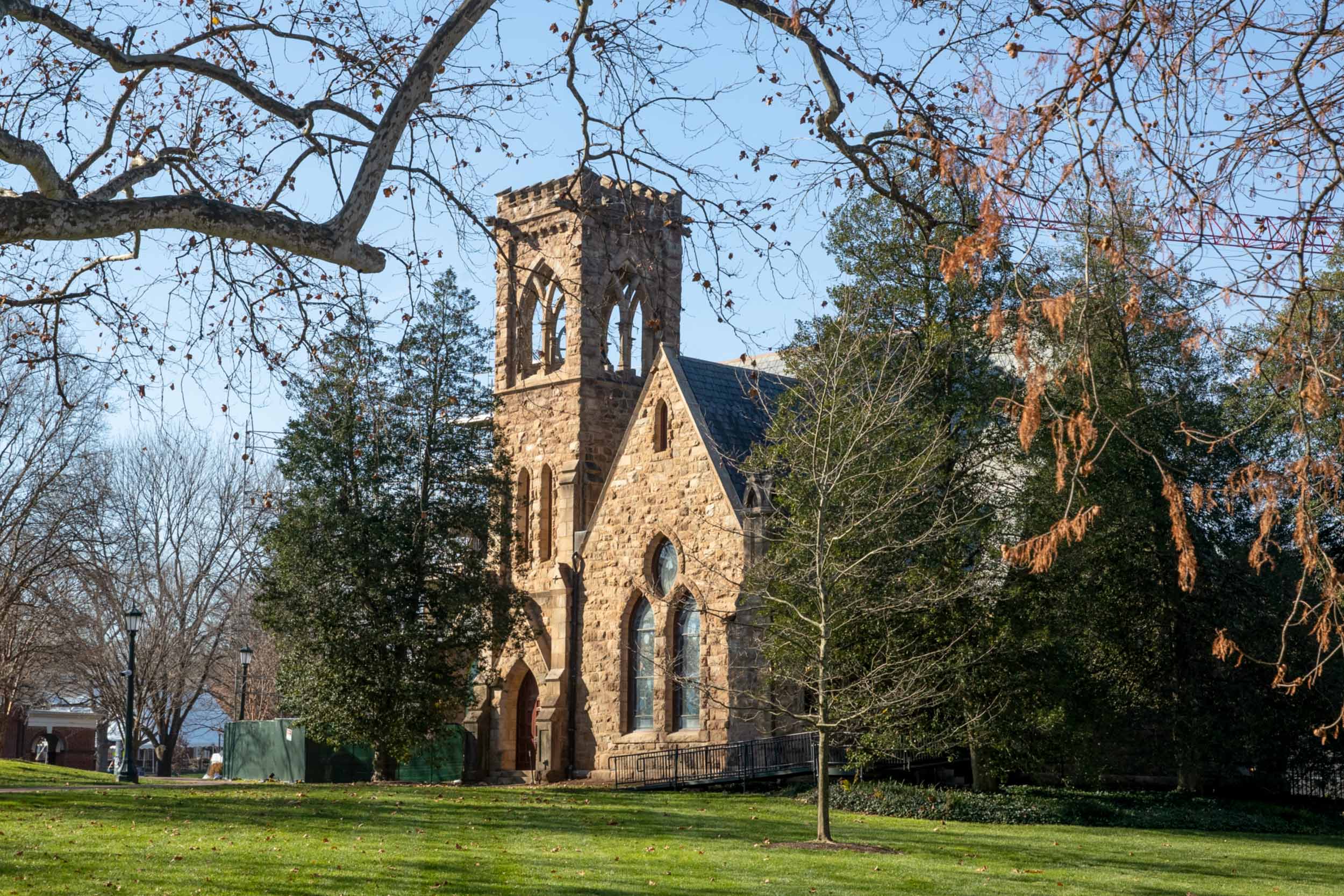 A stone chapel with a bell tower surrounded by trees.