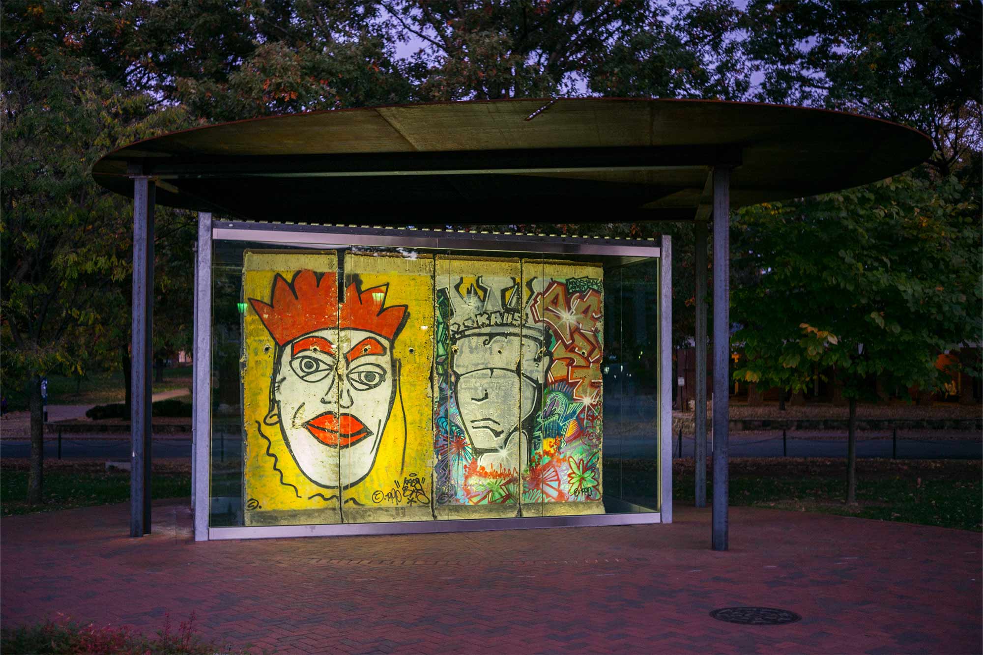 Two graffitied wall panels on display under an awning