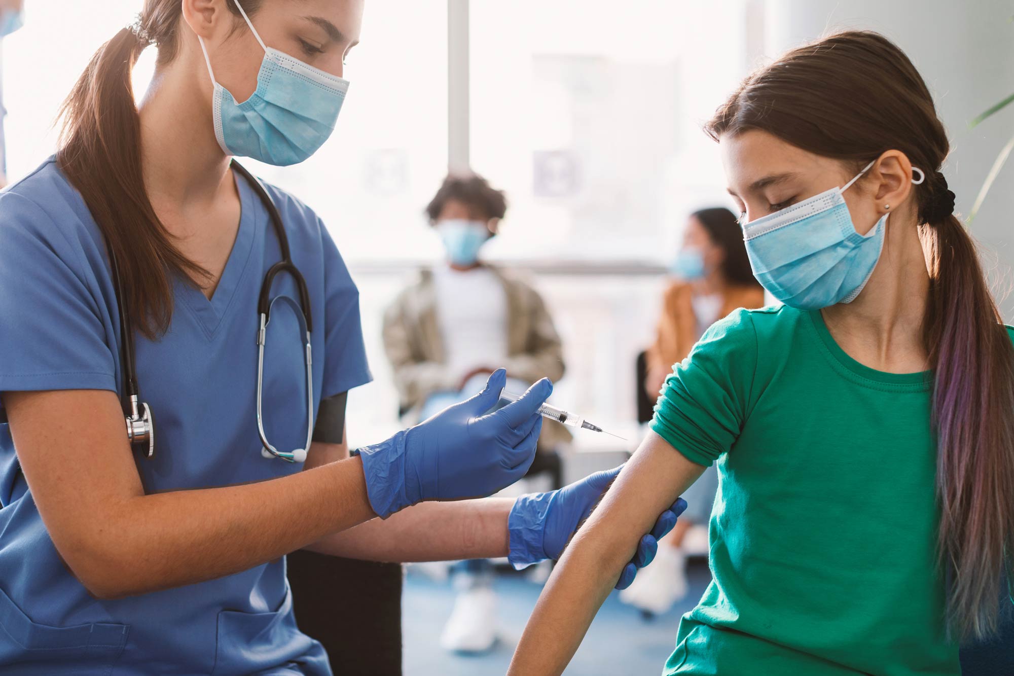 A nurse injects a vaccine into a young girl's upper right arm