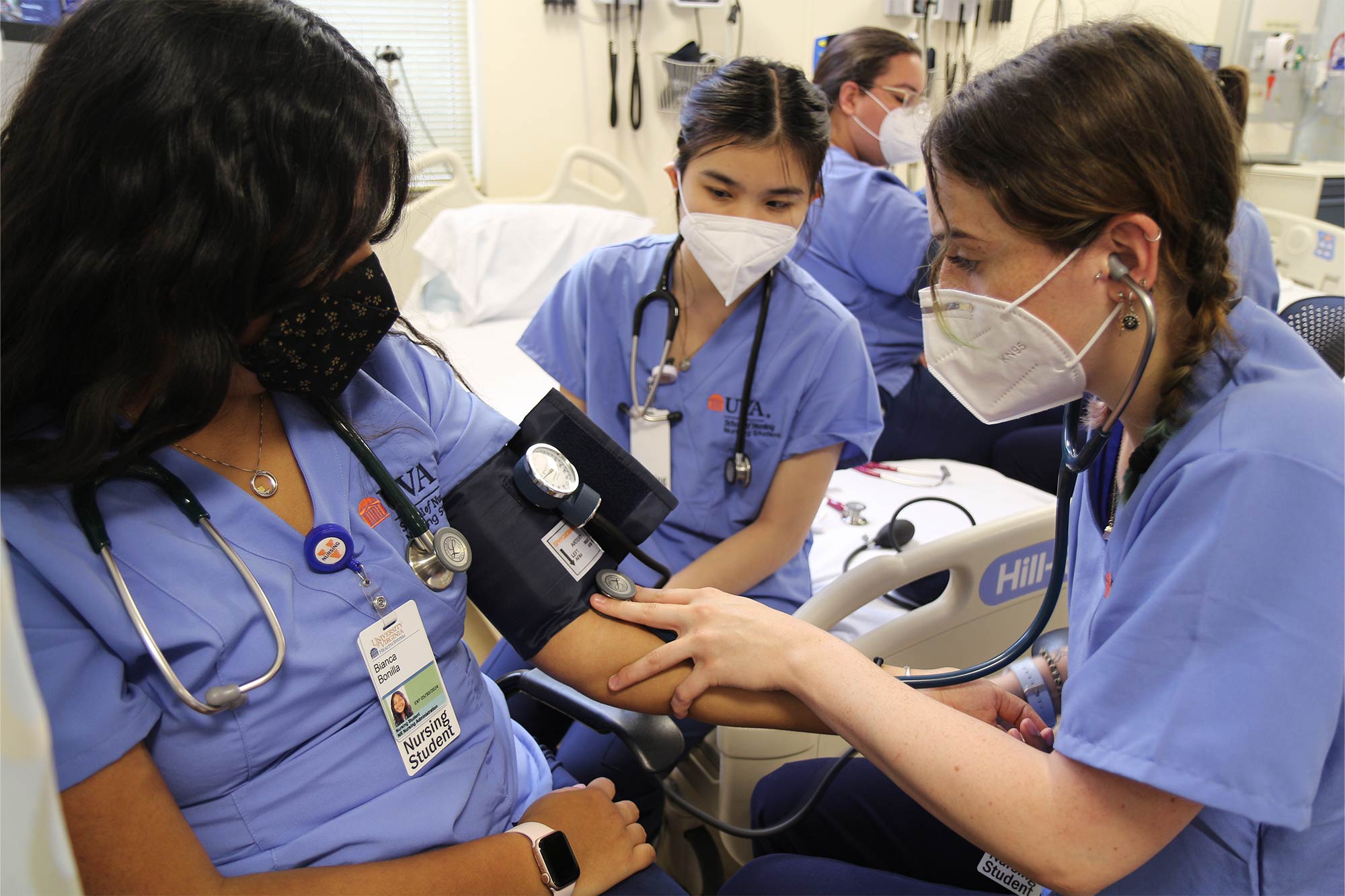 Three nursing students practice taking one another's blood pressure. 