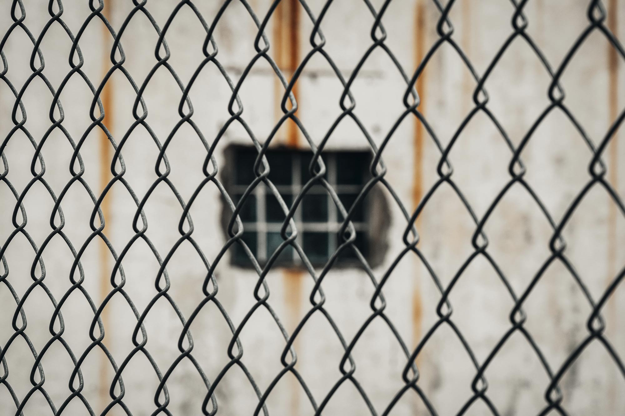 A concrete wall is visible through a chainlink fence